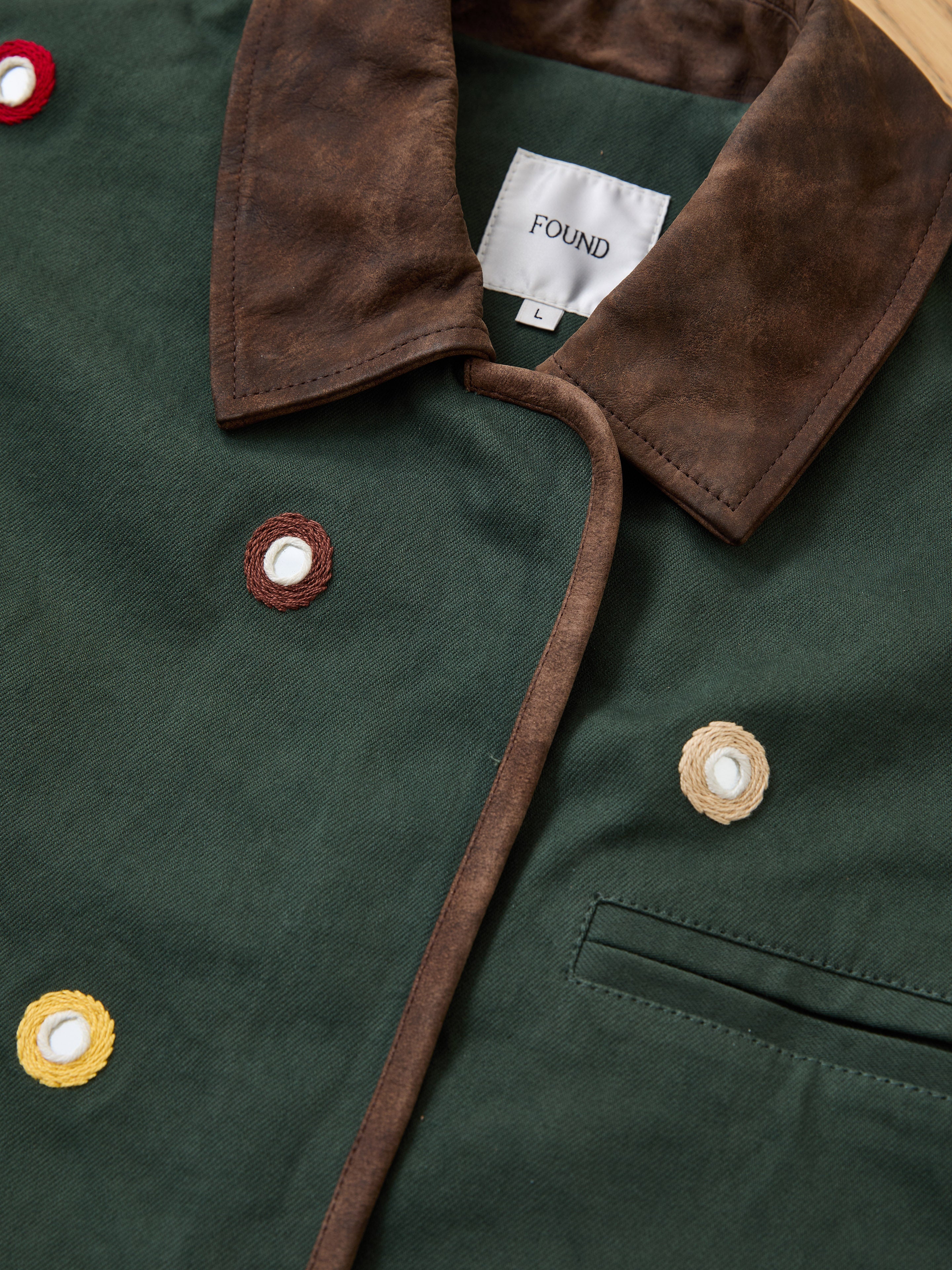 A dark green, artisan-made Found Hand Embroidered Mirror Abhala Jacket featuring a brown collar, chest pocket, multicolored button accents, and a "FOUND" label.