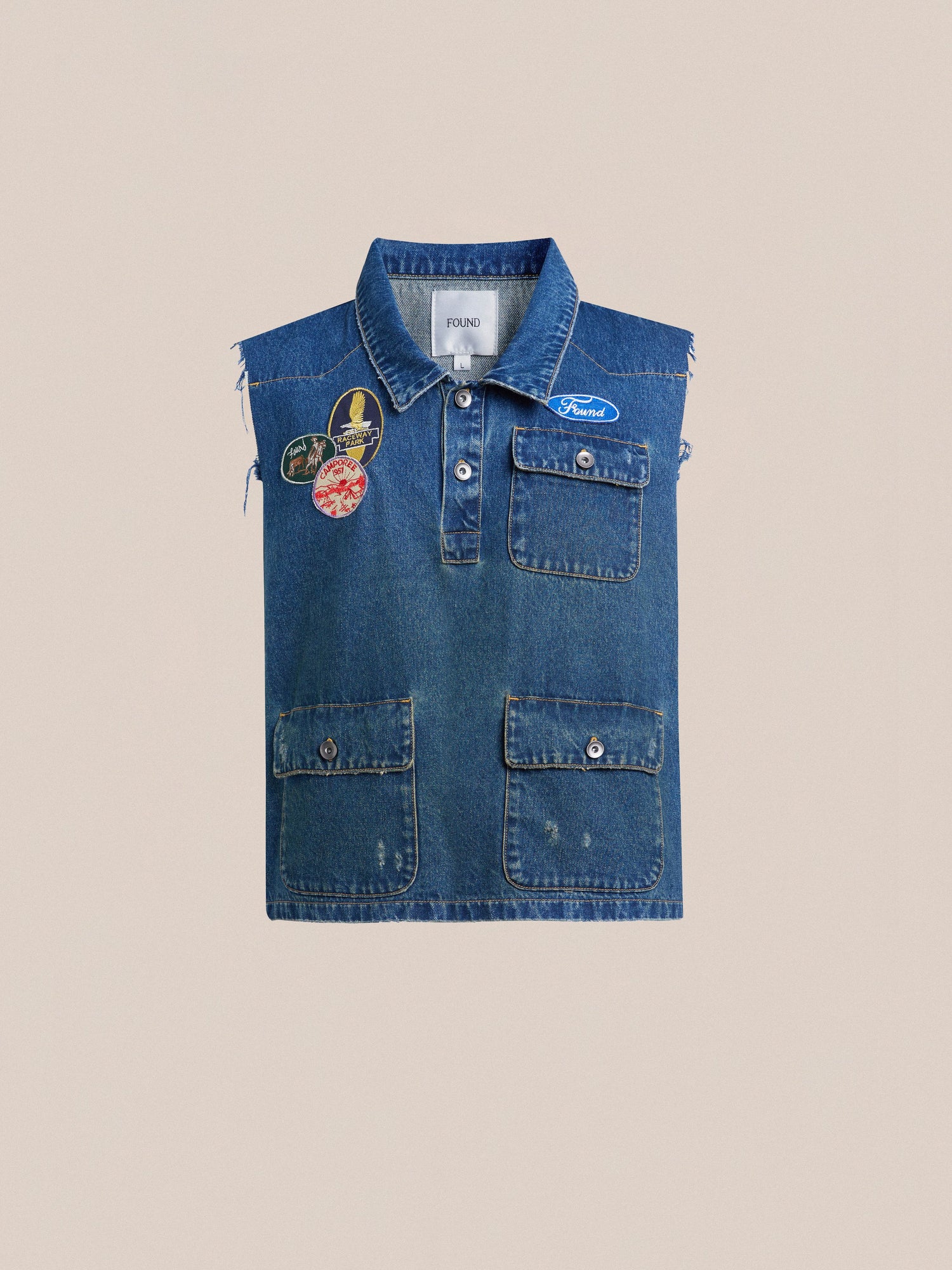 Found's Raw Cut Patch Mechanic Denim Vest, displayed flat against a beige background, featuring a front button closure and chest pockets.