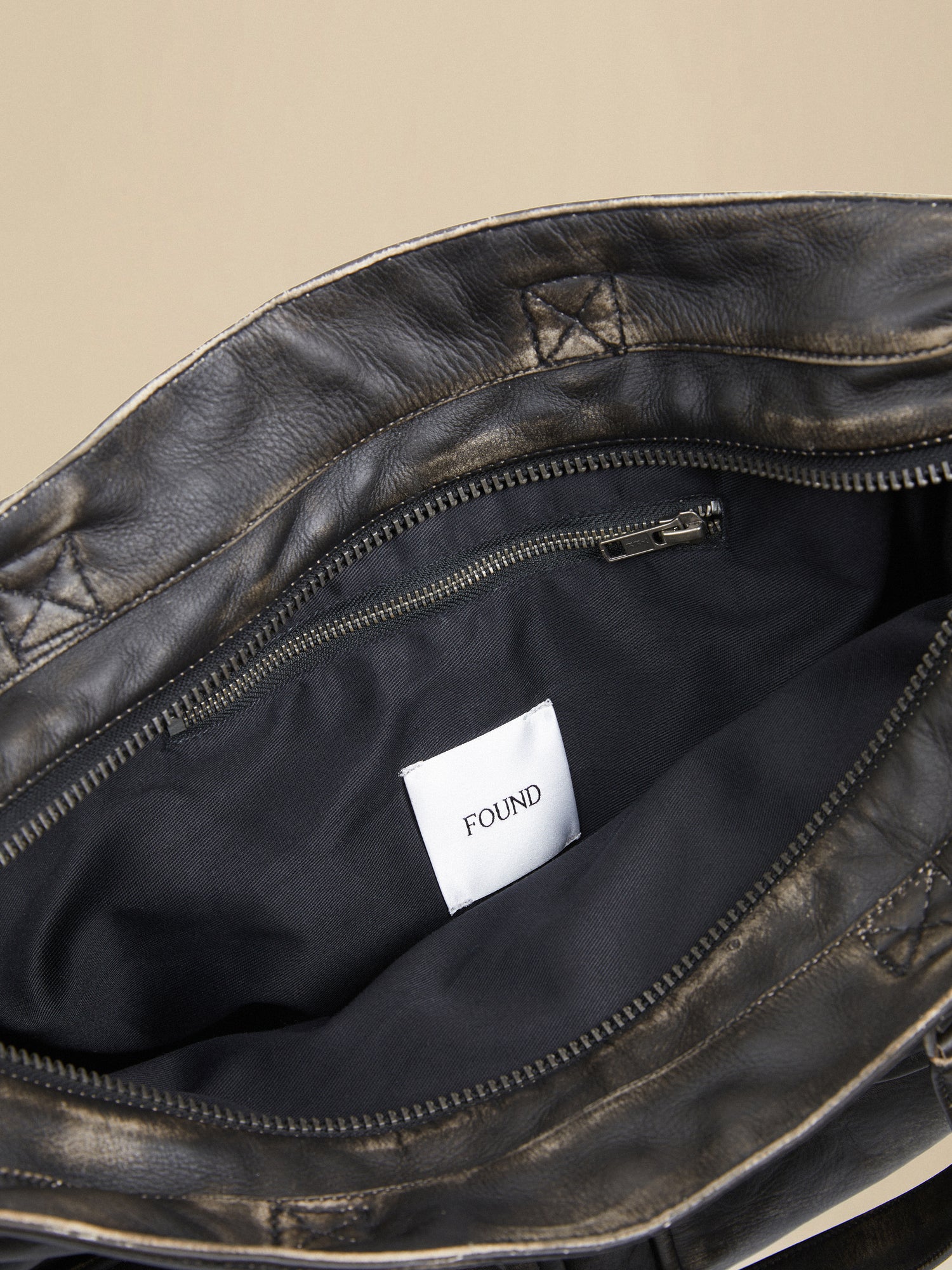 A Profound Hana distressed black leather bag with a label on it, crafted from premium distressed leather.