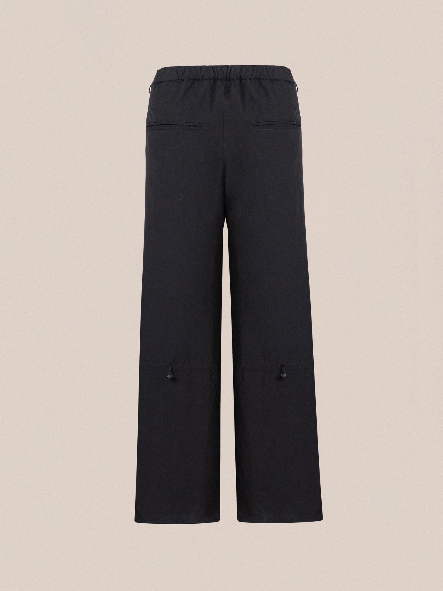 Black Tencel Pleated Pants with an elastic waistband and two side pockets, displayed against a beige background by Found.