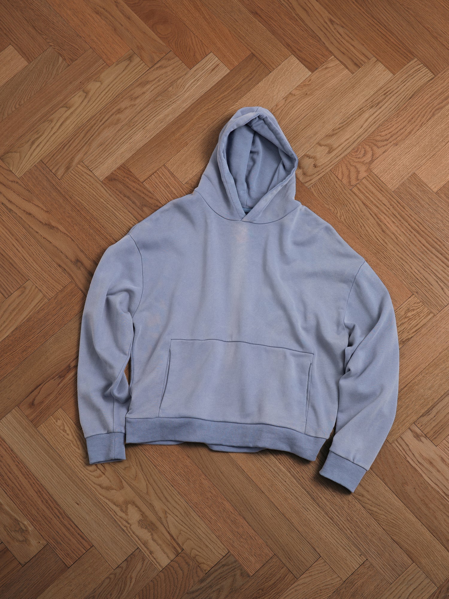 A Faded Infinity Hoodie by Found on a wooden floor.