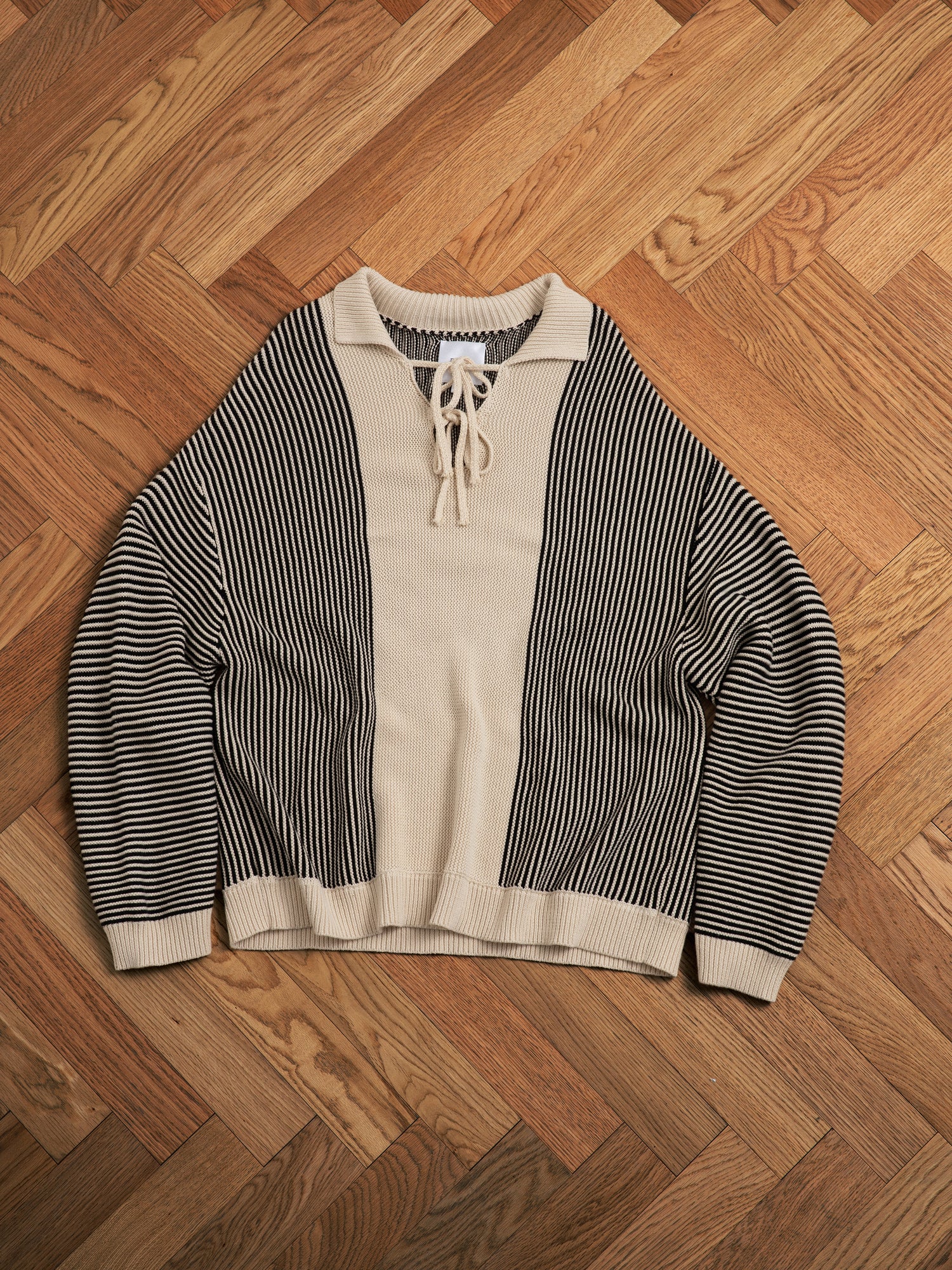 A Tabas Tie Knit Collared Sweater with intricate knit patterns on a wooden floor.