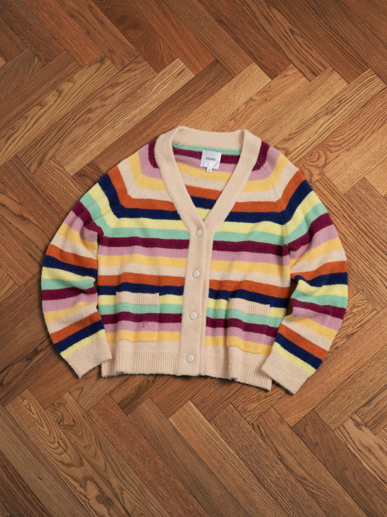 A vibrant hues Found Razi Multi Stripe Cardigan sitting on a wooden floor.
