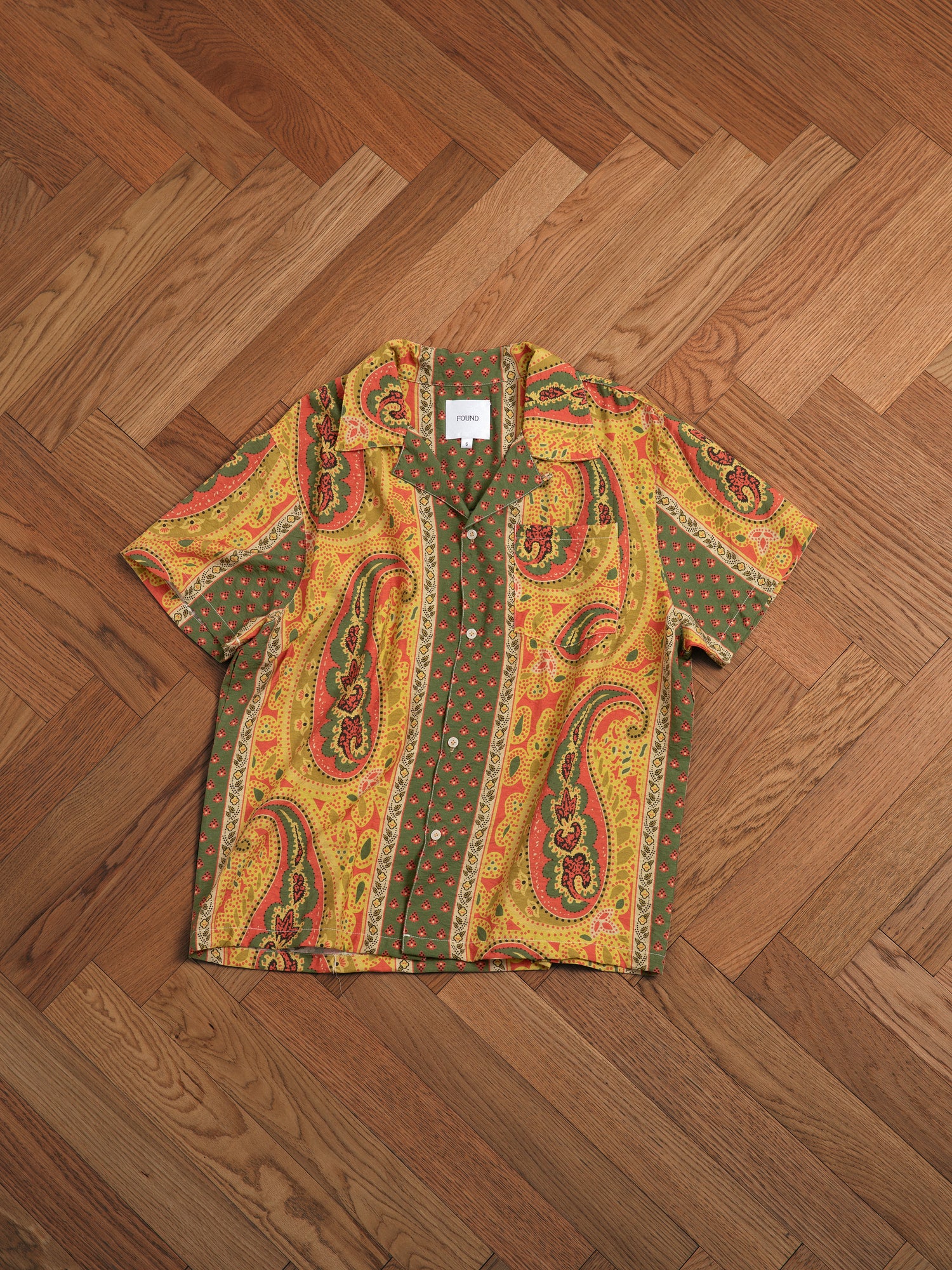 A yellow Pench Paisley SS Camp Shirt on a hardwood floor by Found.