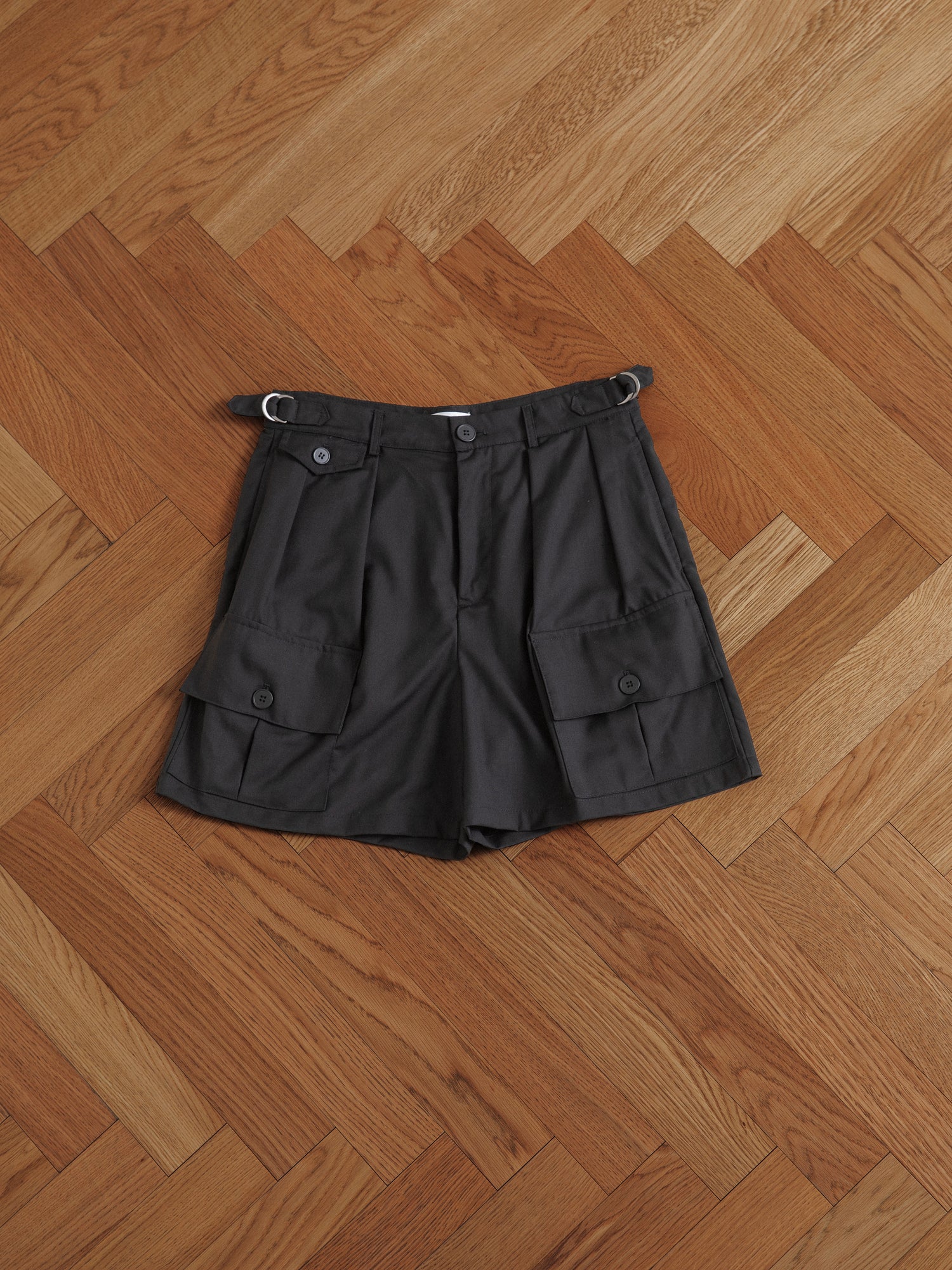 A pair of elegant Found pleated pocket cargo shorts on a wooden floor.