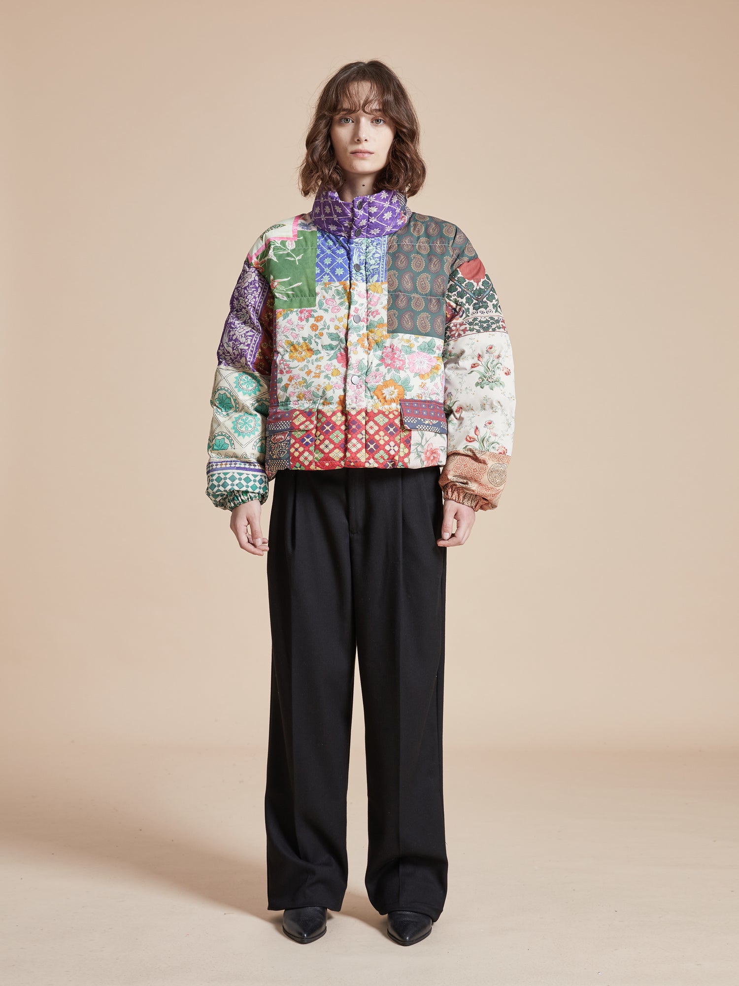 A man wearing a Gardenia Tapestry Puffer Jacket by Found, with traditional South Asian prints.