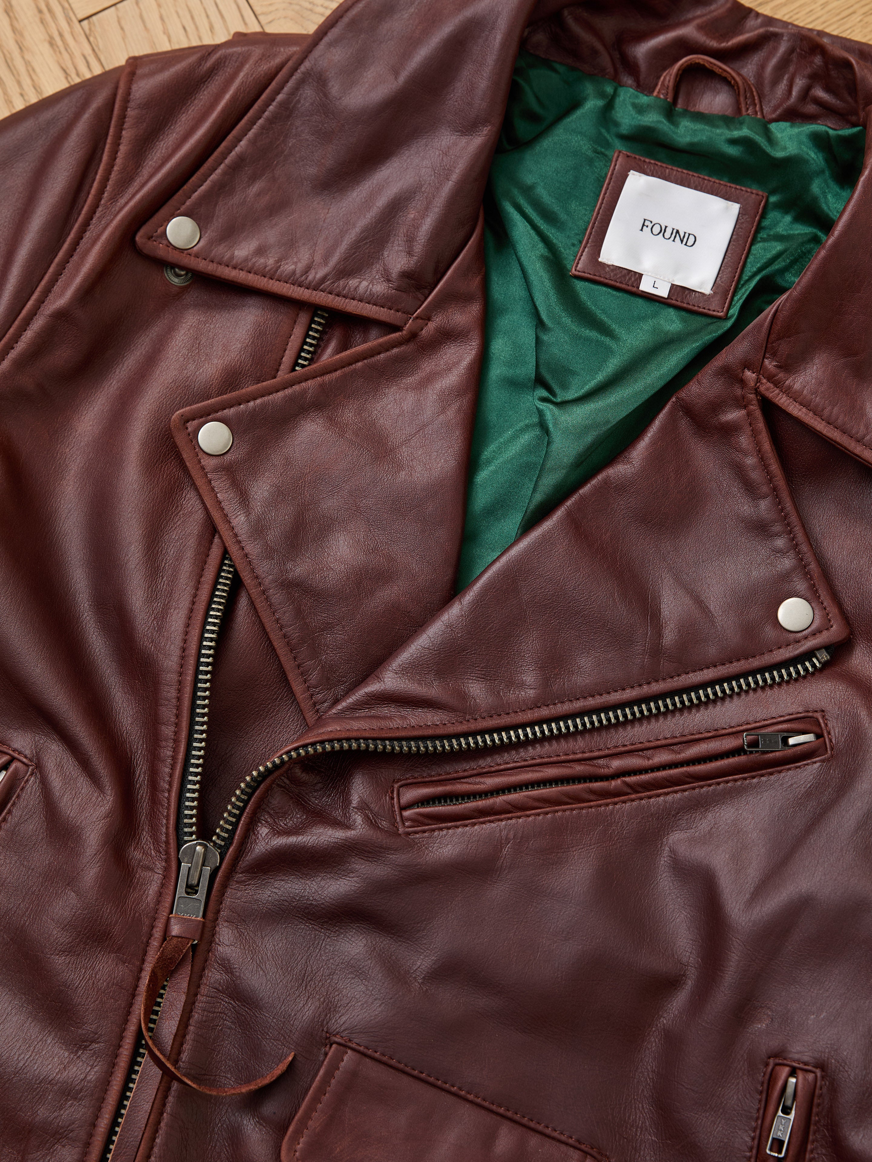 The FOUND Leather Biker Jacket is a unisex brown leather moto with silver zippers, buttons, green lining, and a "FOUND L" label—blending classic style and modern details for versatile edge.