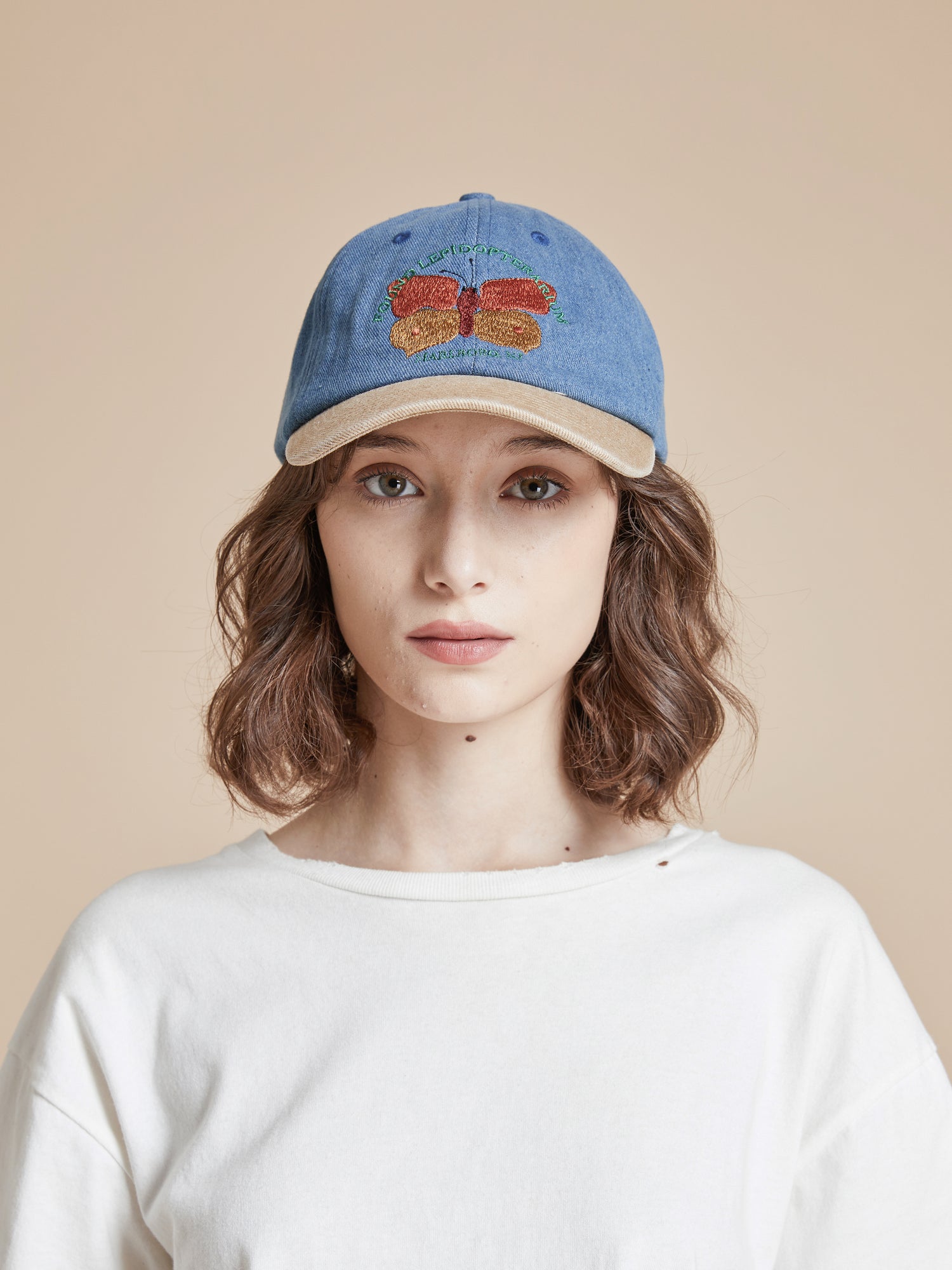 A woman wearing a Butterfly House Denim Cap with an embroidered butterfly on it. (Brand: Found)