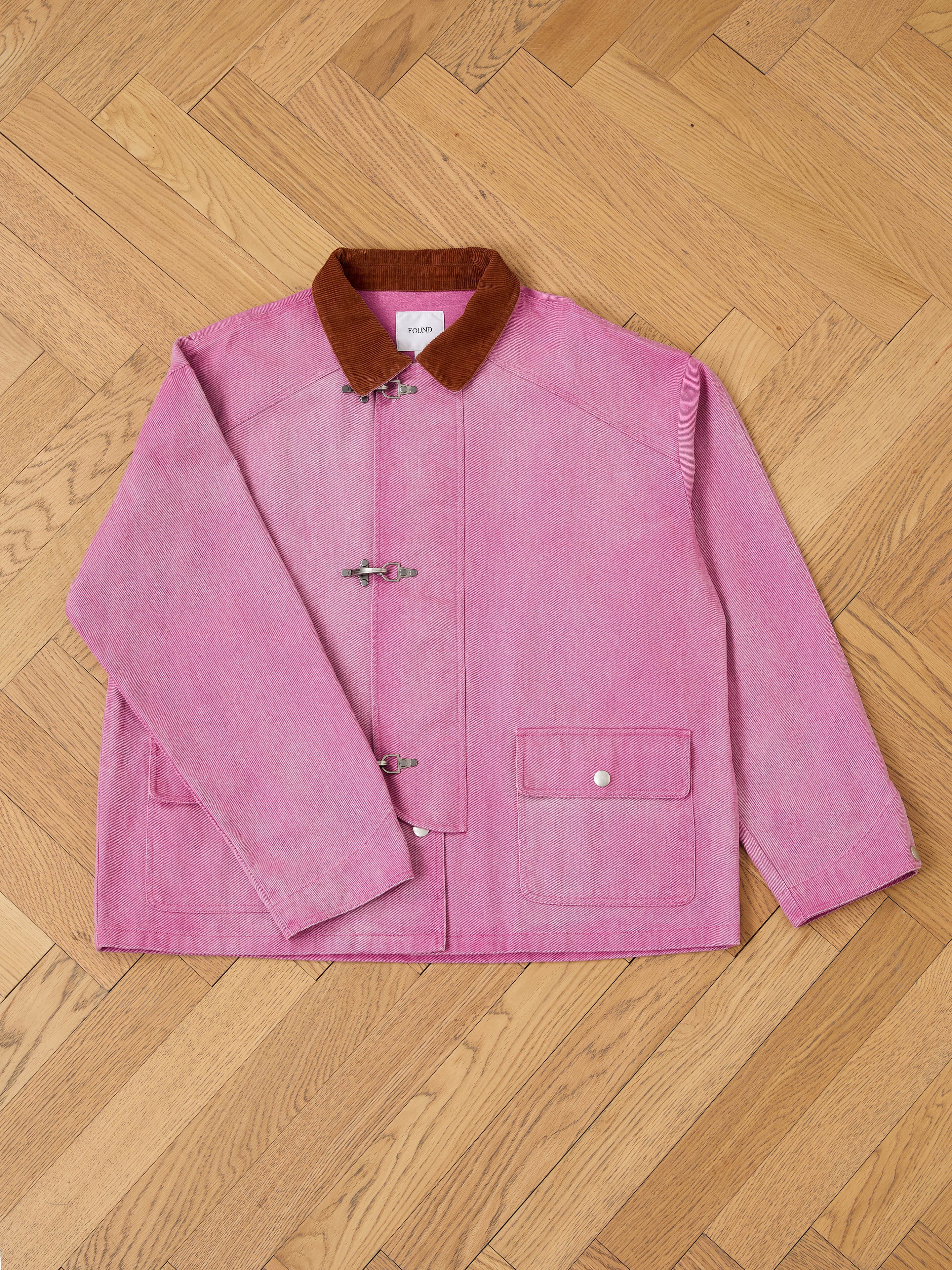 The Found Washed Fireman Clasp Workshop Jacket features a pink corduroy collar, front toggle closures, and two flap pockets, blending vintage fireman style with unisex utility appeal.