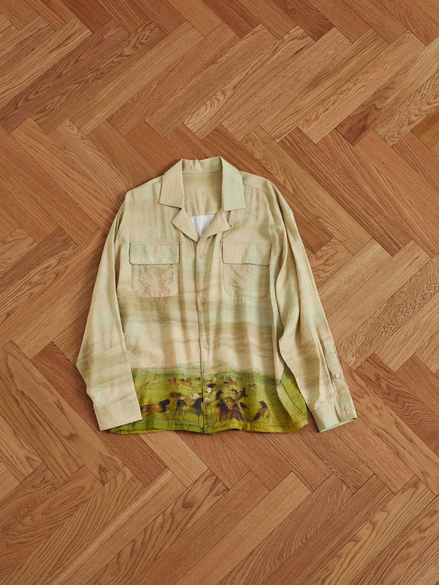 A Grasslands Long Sleeve Camp Shirt with Phulkari motifs on a wooden floor by Found.