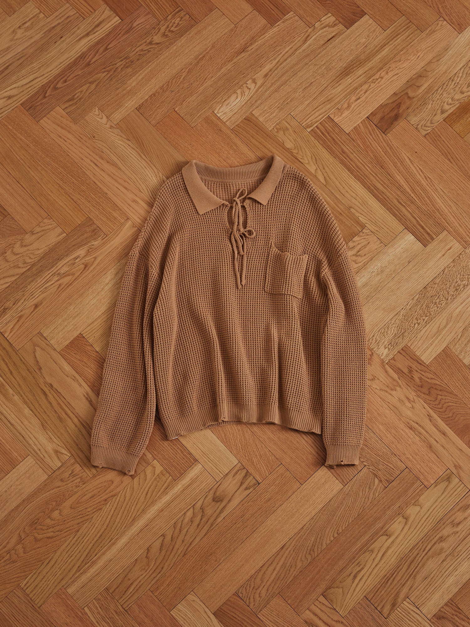 A Found Tie-Collar Knit Sweater in a cozy feel on a wooden floor.