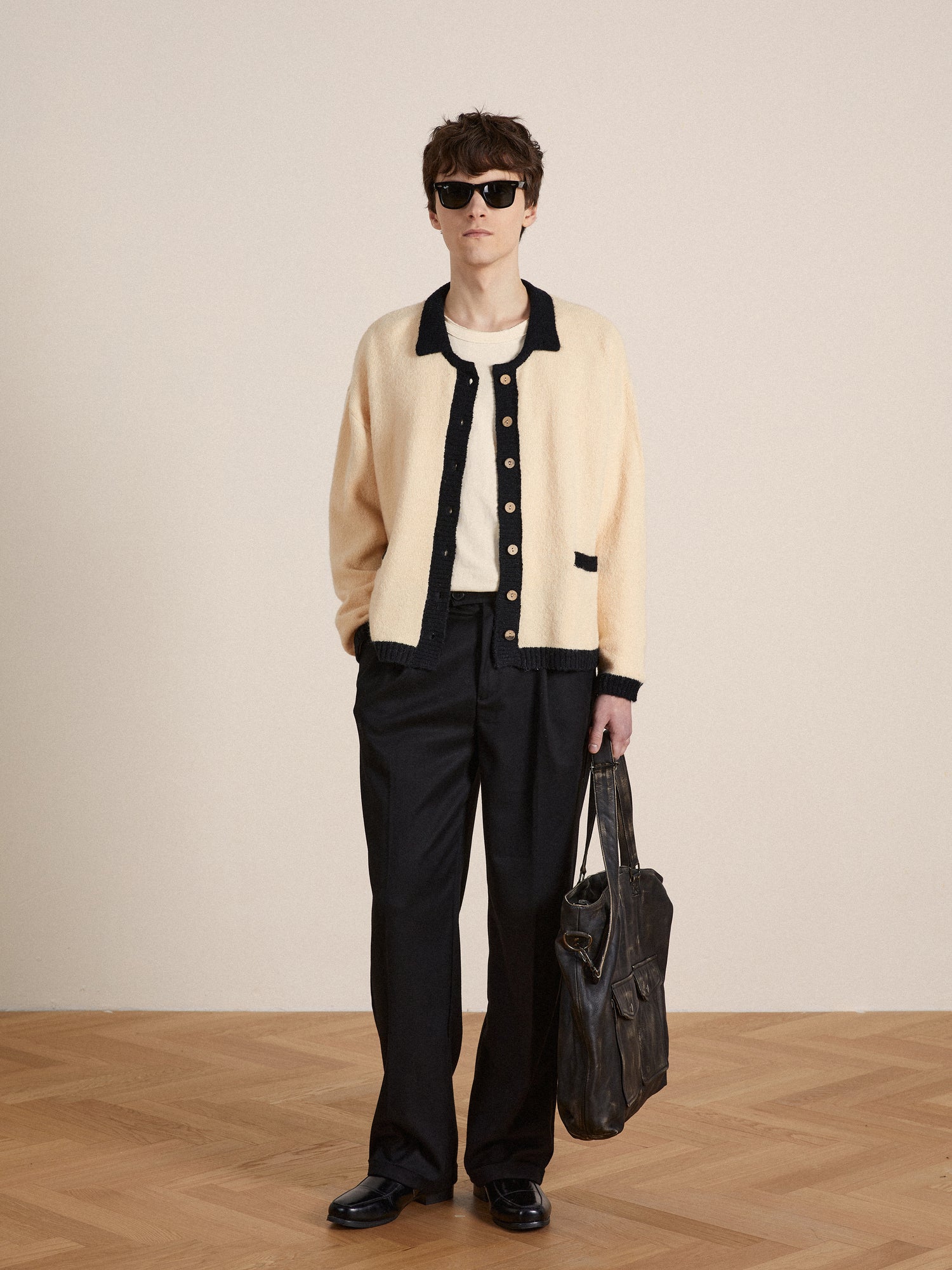 A man in a luxurious fuzzy textured fabric Found Sima Contrast Collar Knitted Cardigan and black pants is holding a bag.