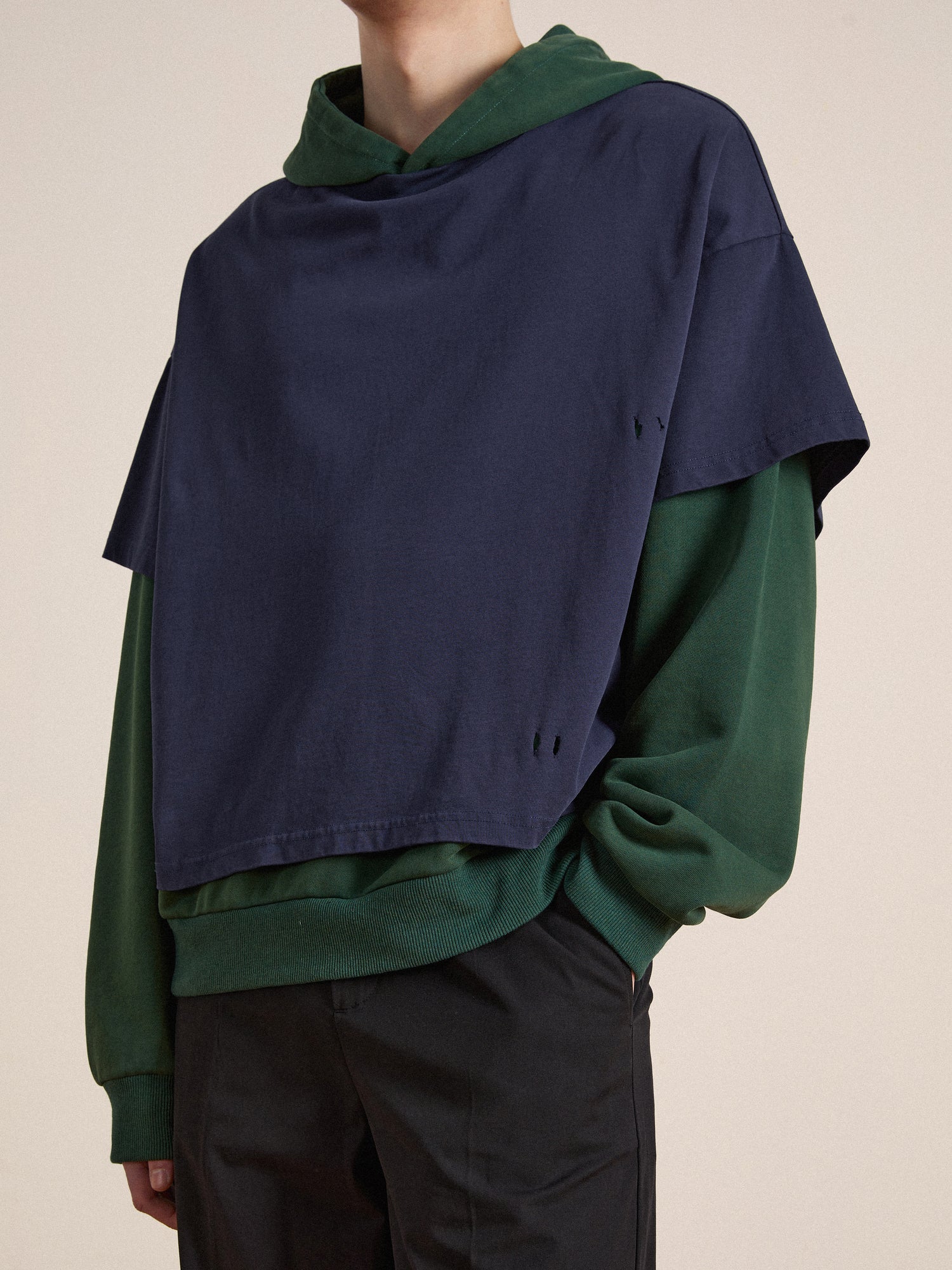 A man wearing a navy Found Double Layer Hoodie and green hoodie.