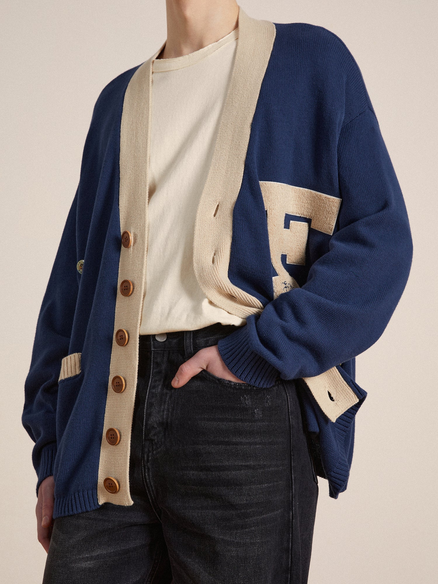 A man wearing a Found Laleh Varsity Contrast Cardigan for a customizable look.