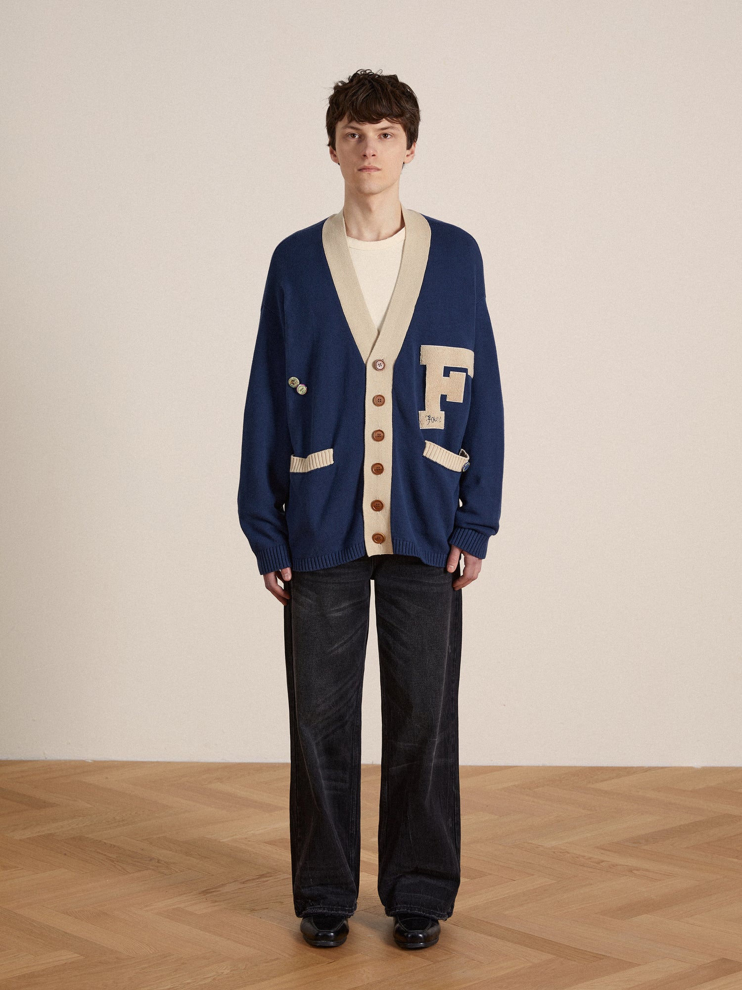 A man donning a vintage Ivy League fashion-inspired Found Laleh Varsity Contrast Cardigan and pants.