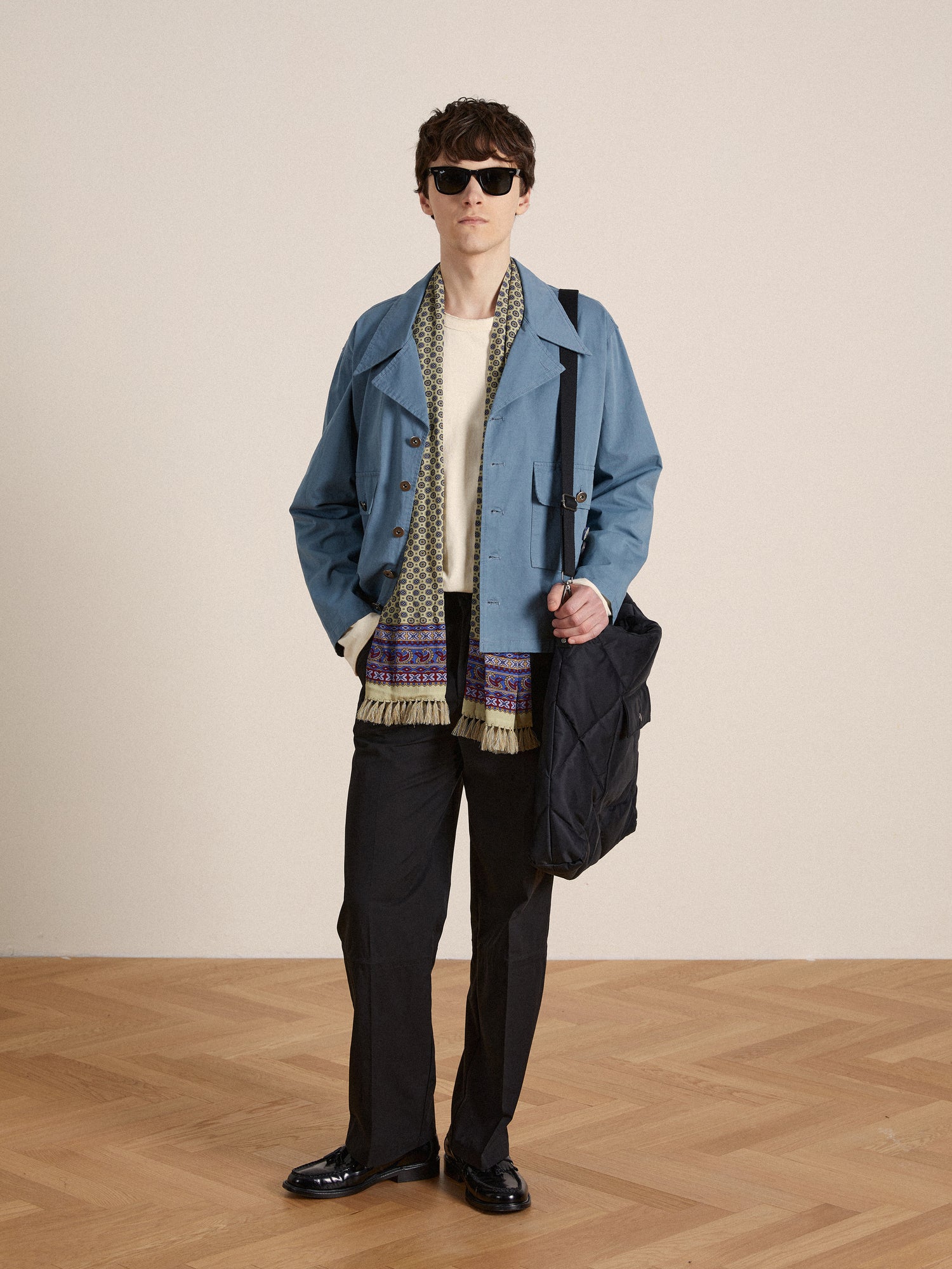 A man in a vintage Found Patina Work Jacket and sunglasses is standing on a wooden floor.