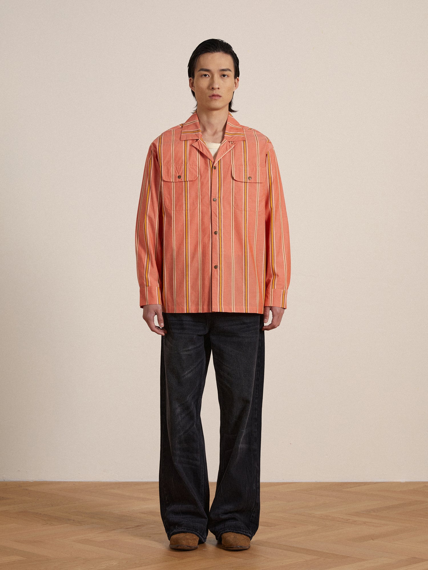 A man in a classic appeal Found Stripe Citrus LS Camp Shirt standing on a wooden floor.