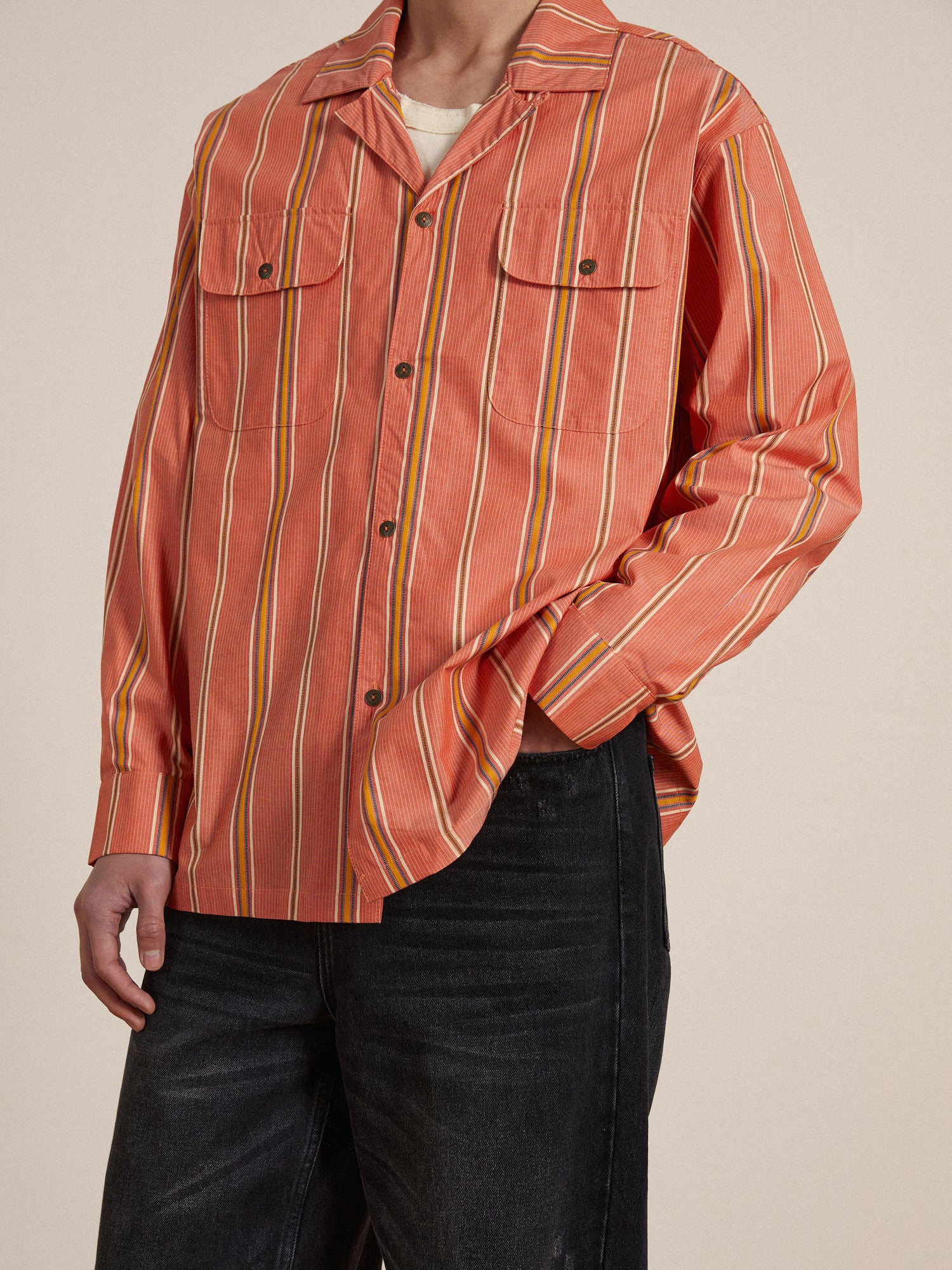 A man wearing an orange Found Stripe Citrus Long Sleeve Camp Shirt and jeans.