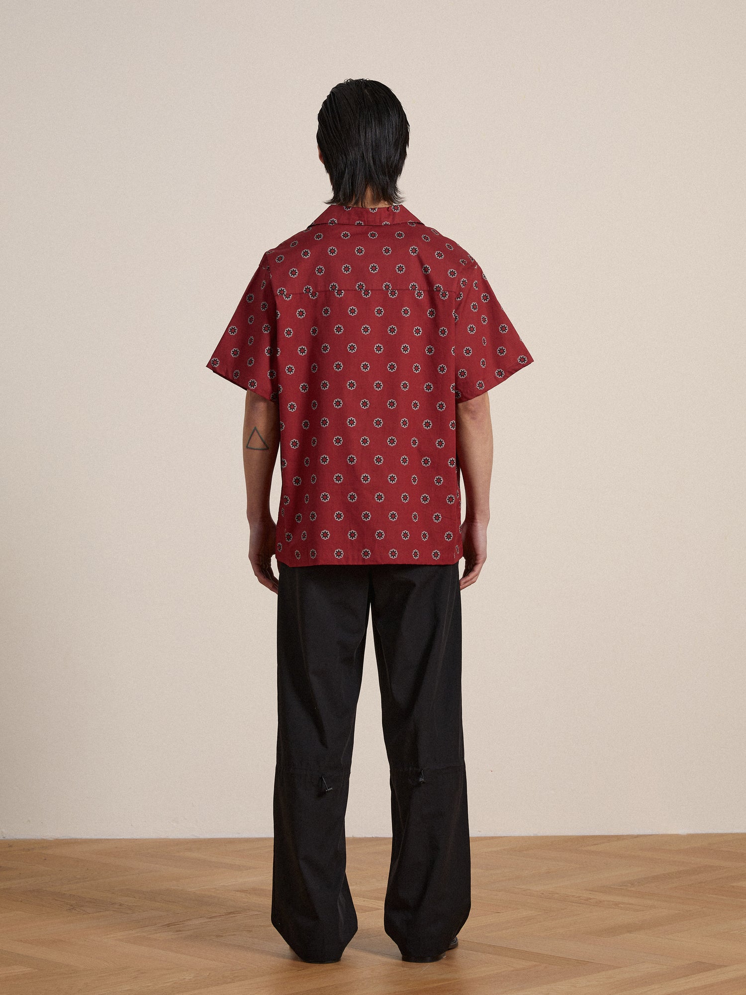 The back of a man wearing a Found Red Motif SS Camp Shirt and black pants.