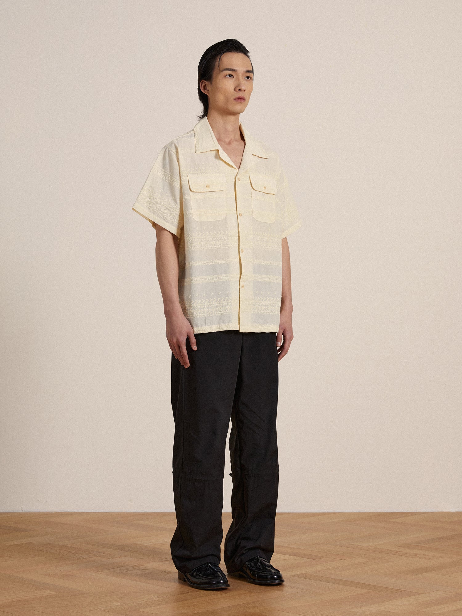 A man wearing a Found premium cotton Lace SS Camp Shirt and black pants.