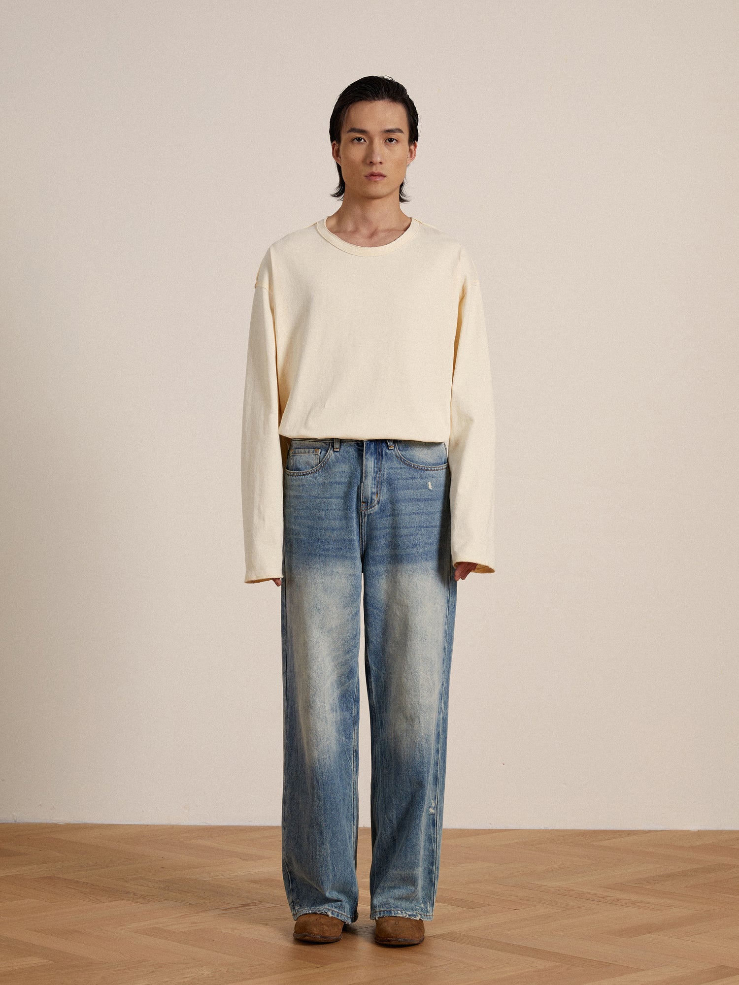 The model is wearing a white Profound Reversed LS Tee with reversed seams and blue jeans.