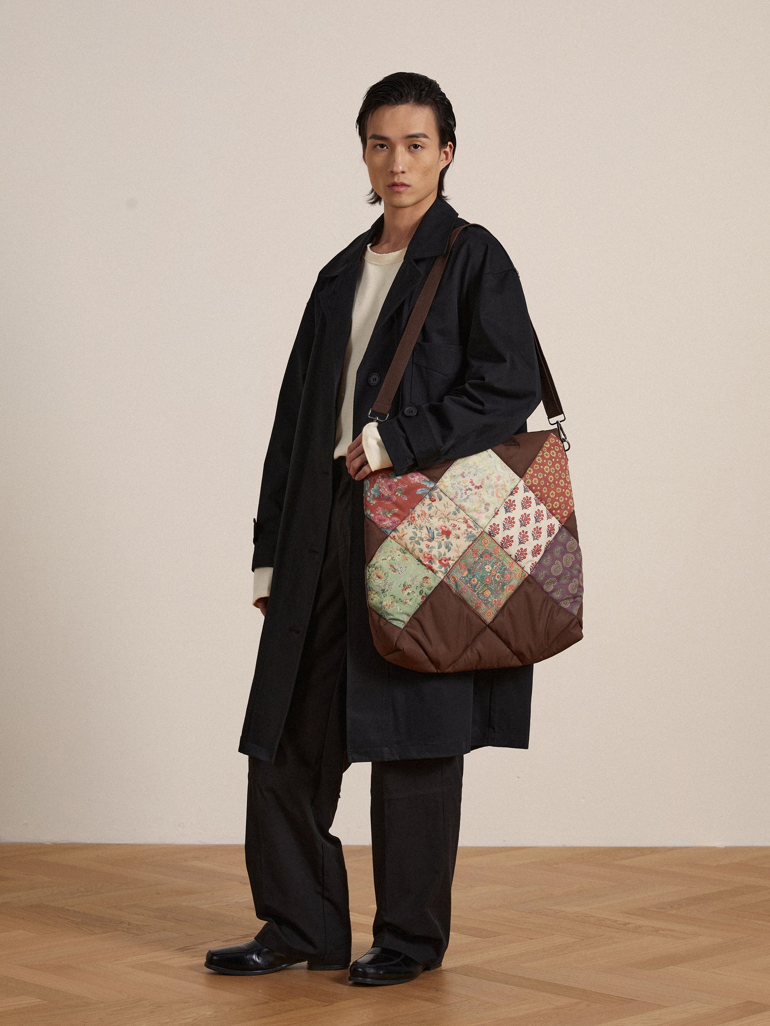 A man is holding a Profound Parisa Quilted Tapestry Bag with a patchwork pattern.