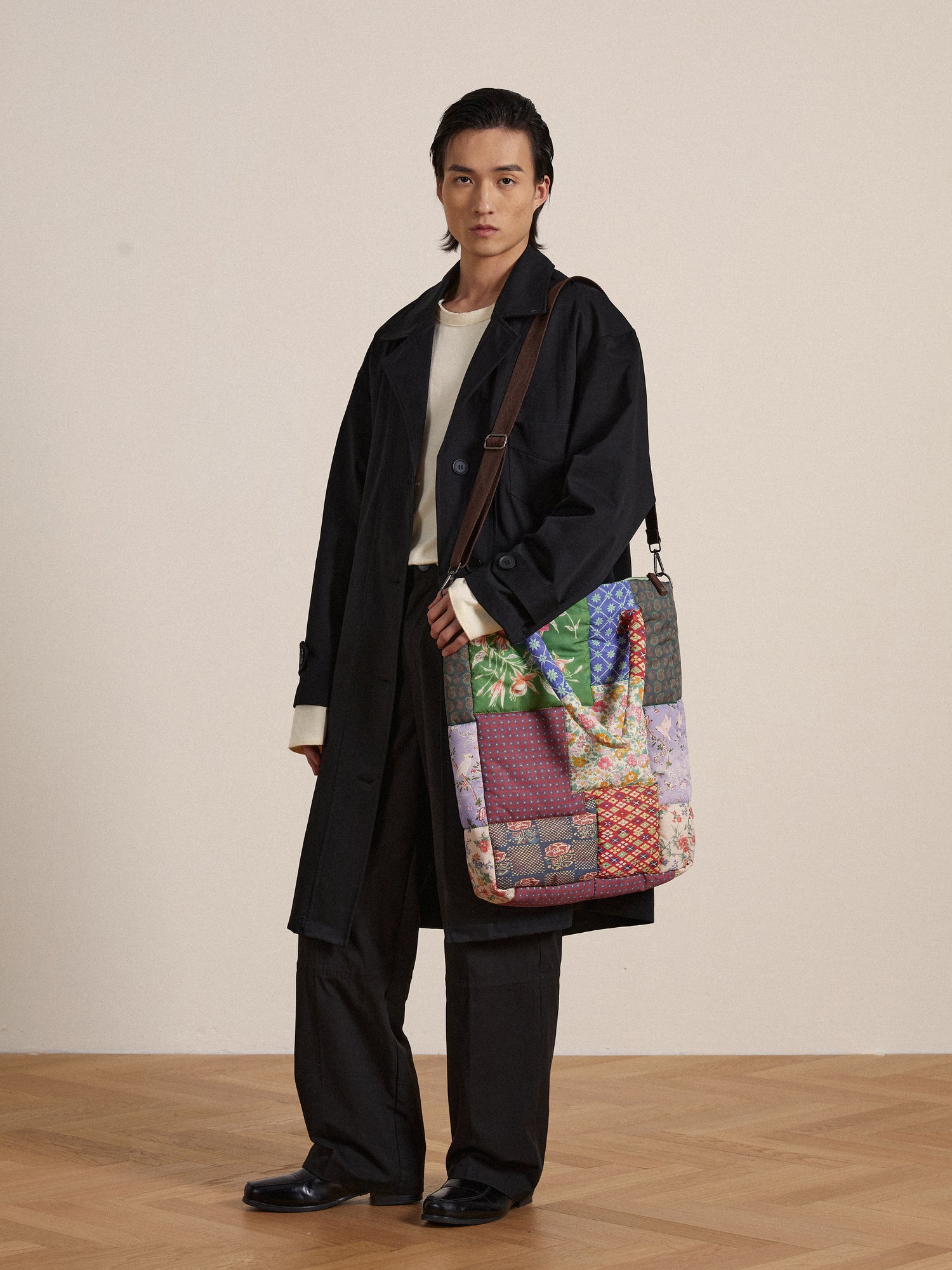 A man in a trench coat holding a Profound Gardenia Tapestry Bag showcasing South Asian prints.