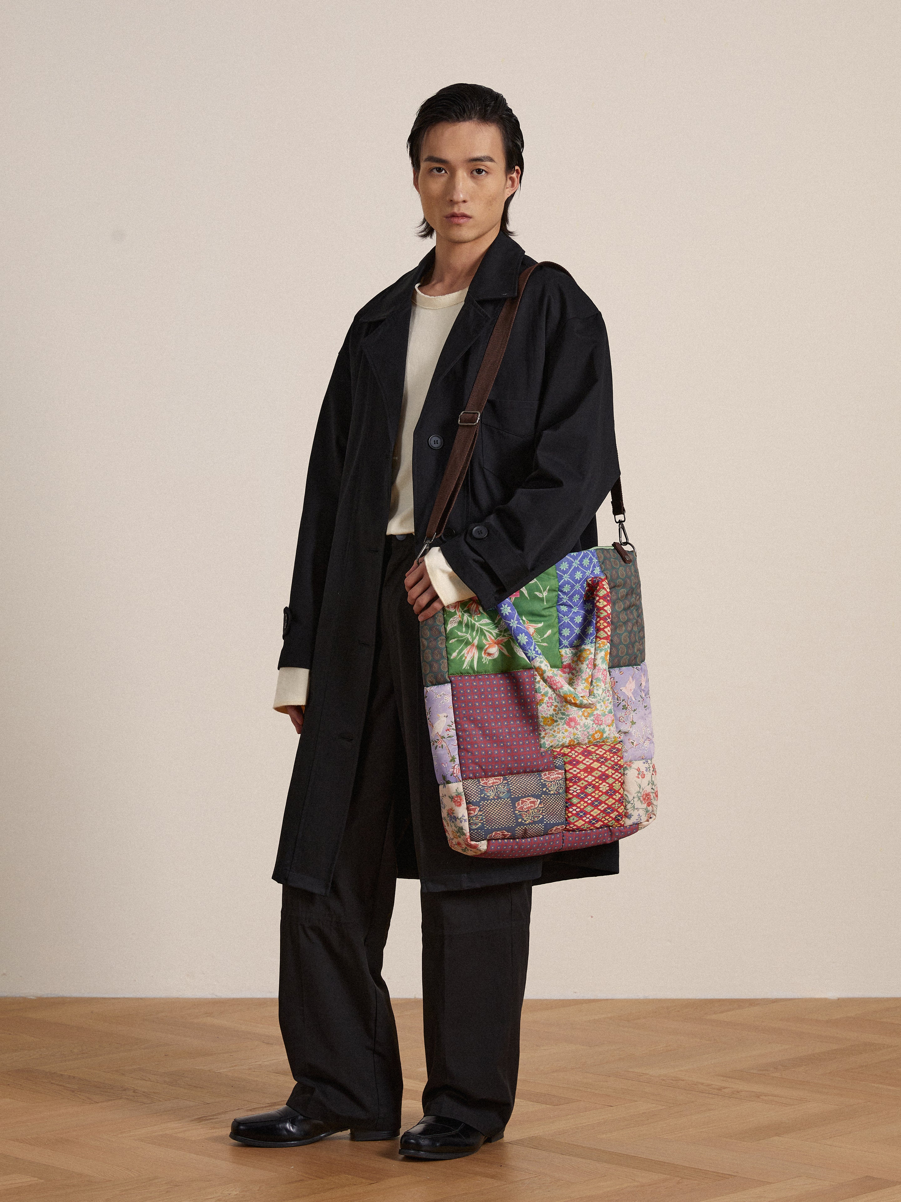 A man in a trench coat holding a Profound Gardenia Tapestry Bag showcasing South Asian prints.