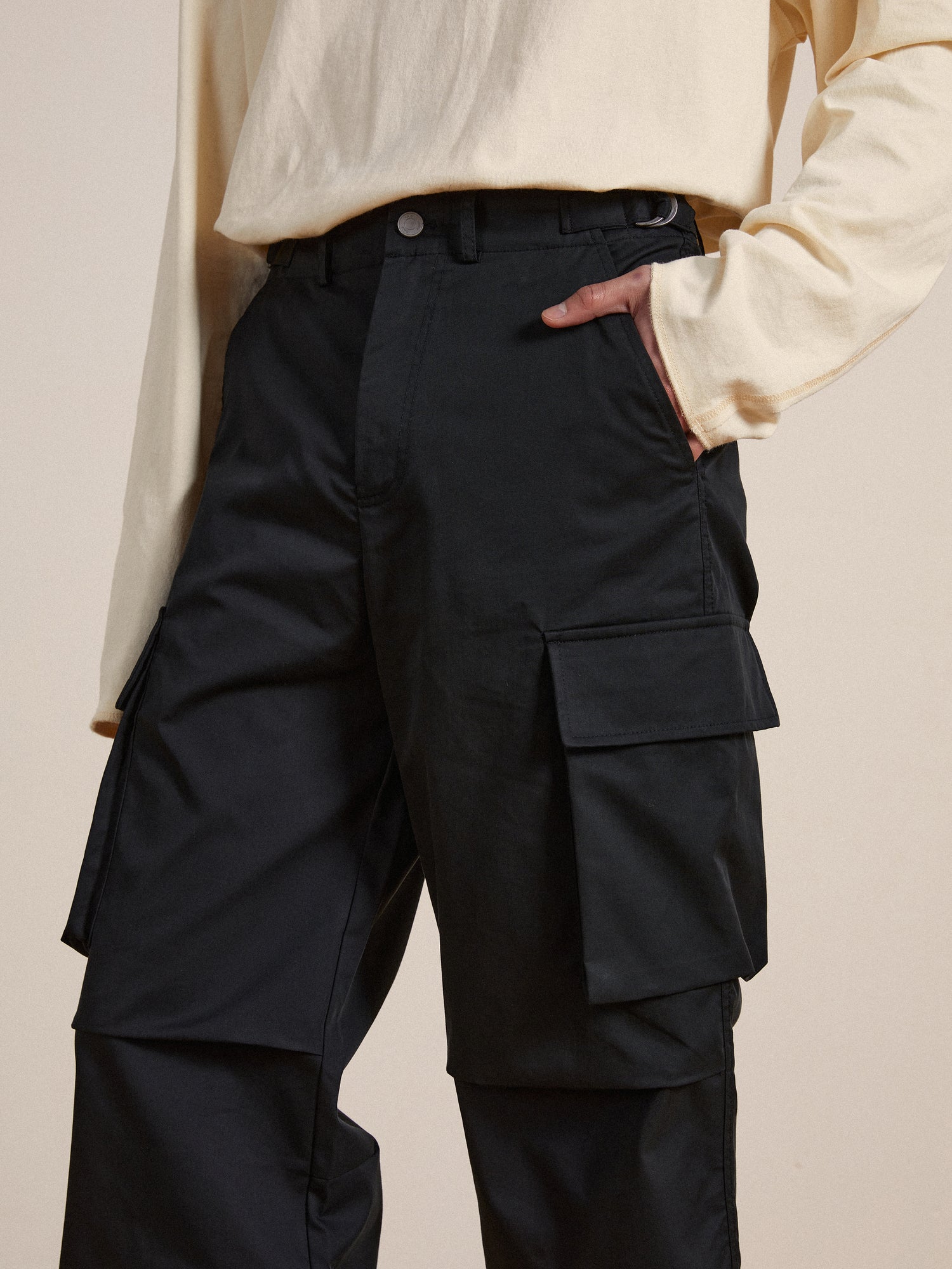 A man wearing black Elbas cargo pants with adjustable waist tabs and a white tee.