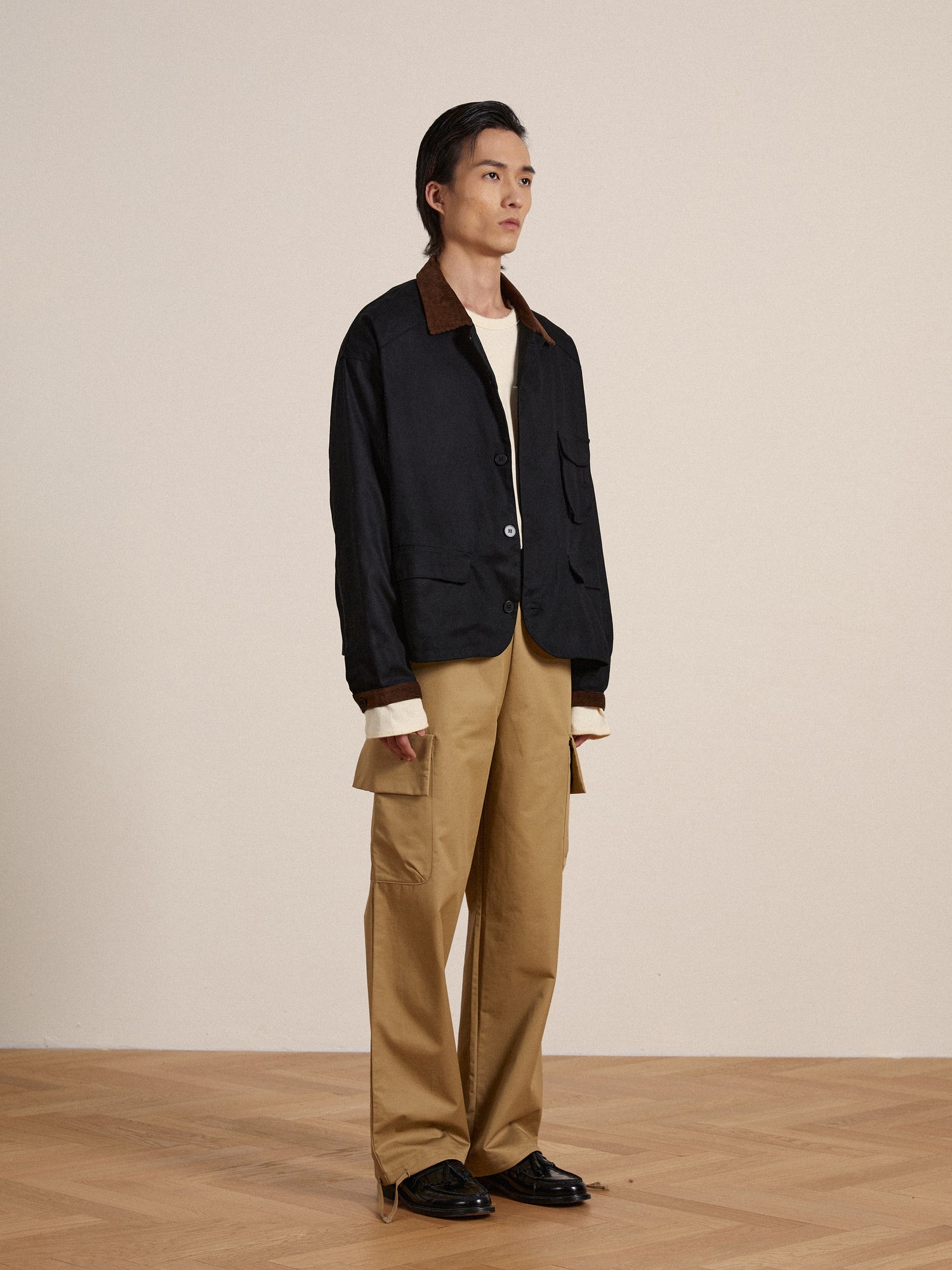 A model wearing a Found Lar Waxed Cotton Box Coat jacket and khaki pants for protection.