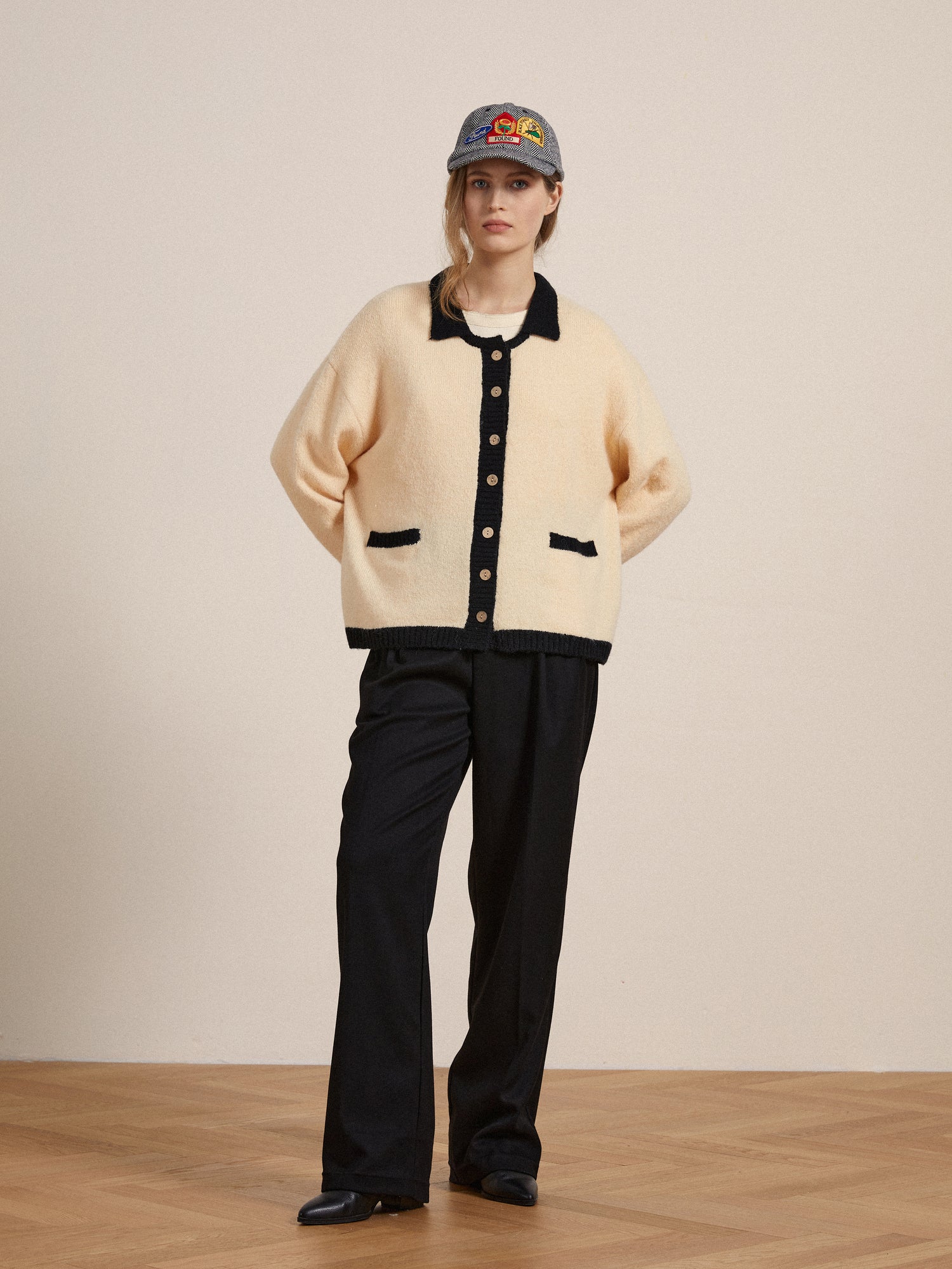 A woman wearing a Found Sima Contrast Collar Knitted Cardigan with wooden buttons and black pants.