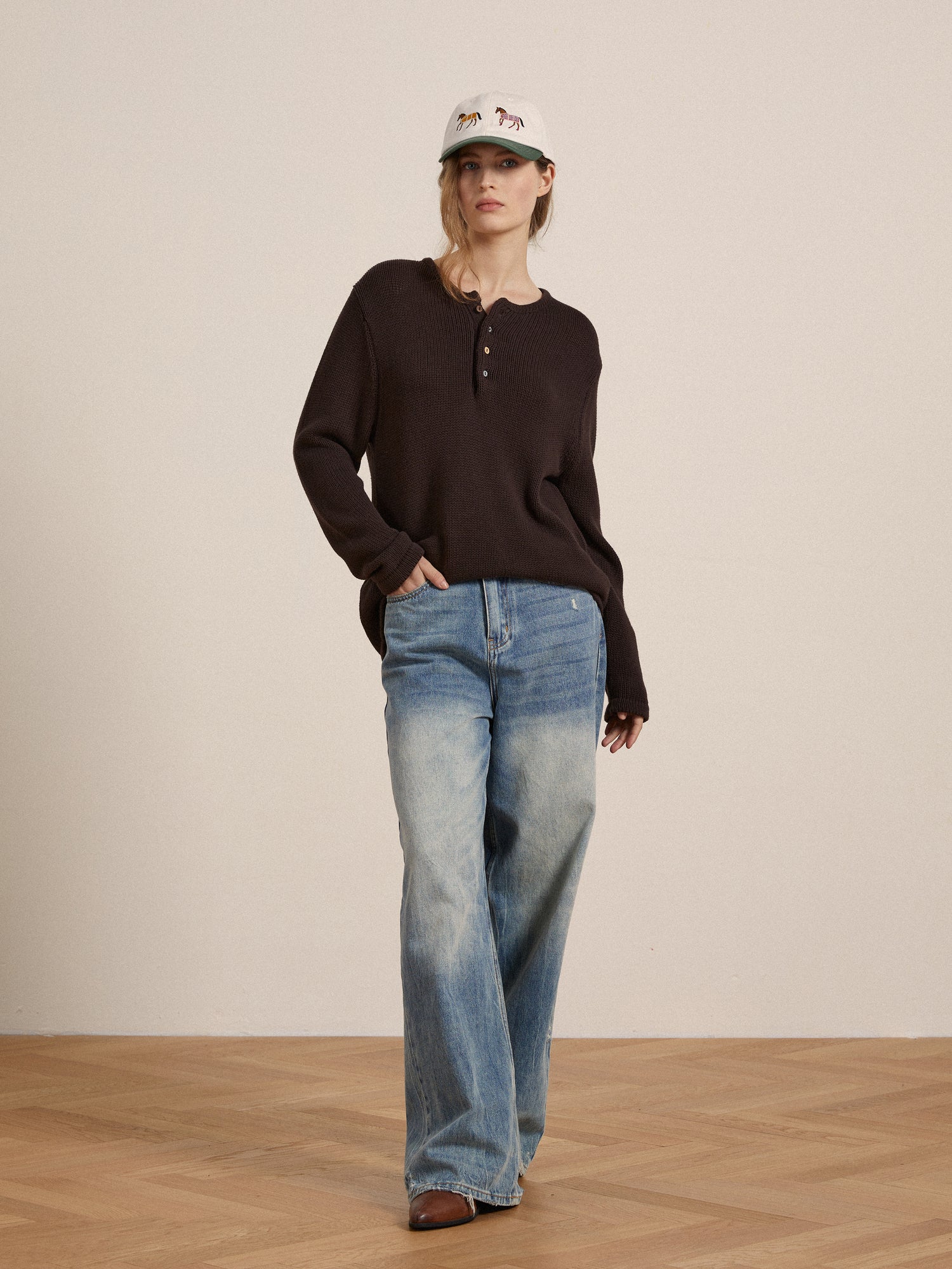 The model is wearing a brown Profound knit Henley sweater with a button-up design and jeans.