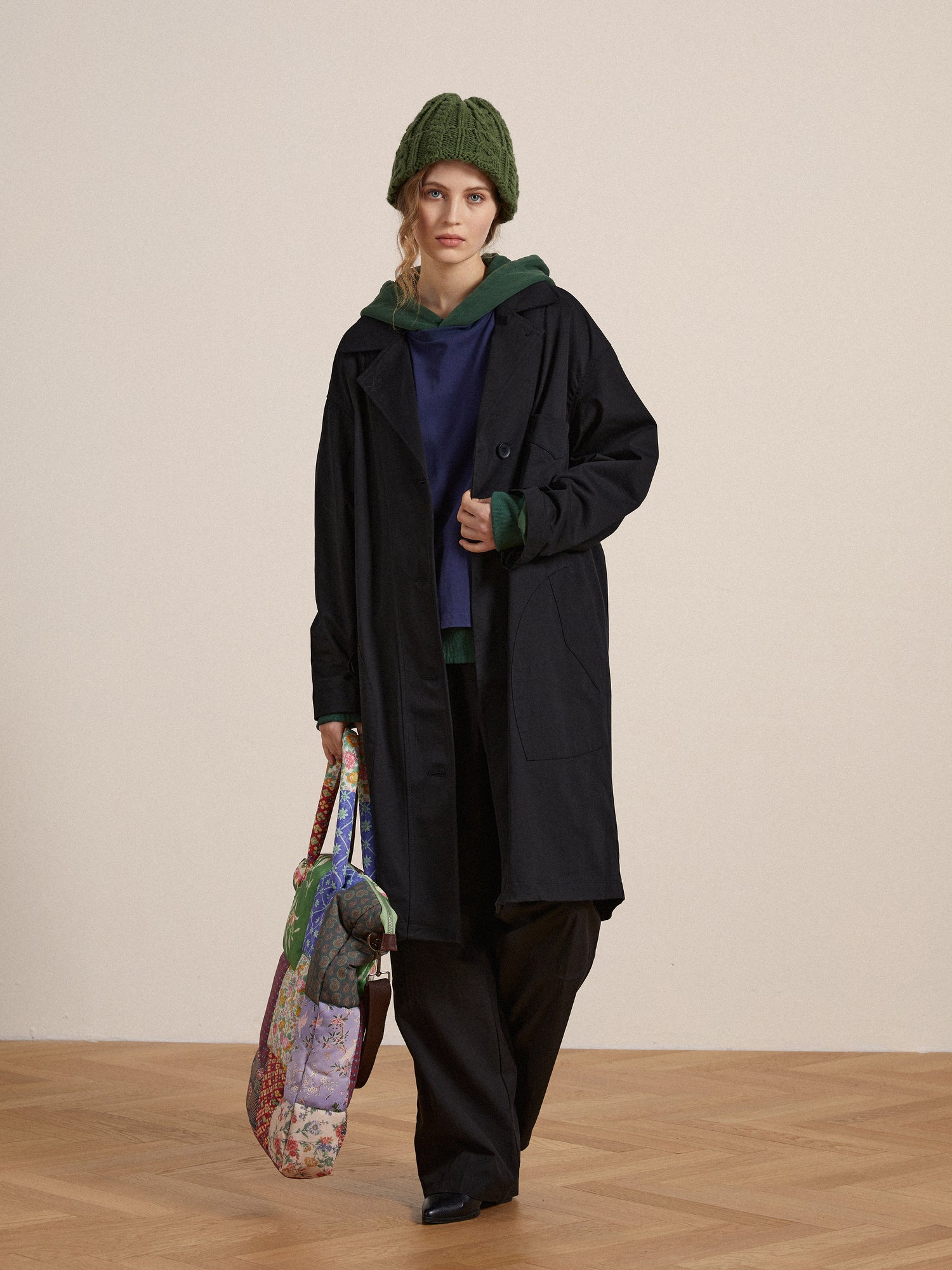 A woman wearing a trench coat and a hat and carrying a Found Double Layer Hoodie tote bag.