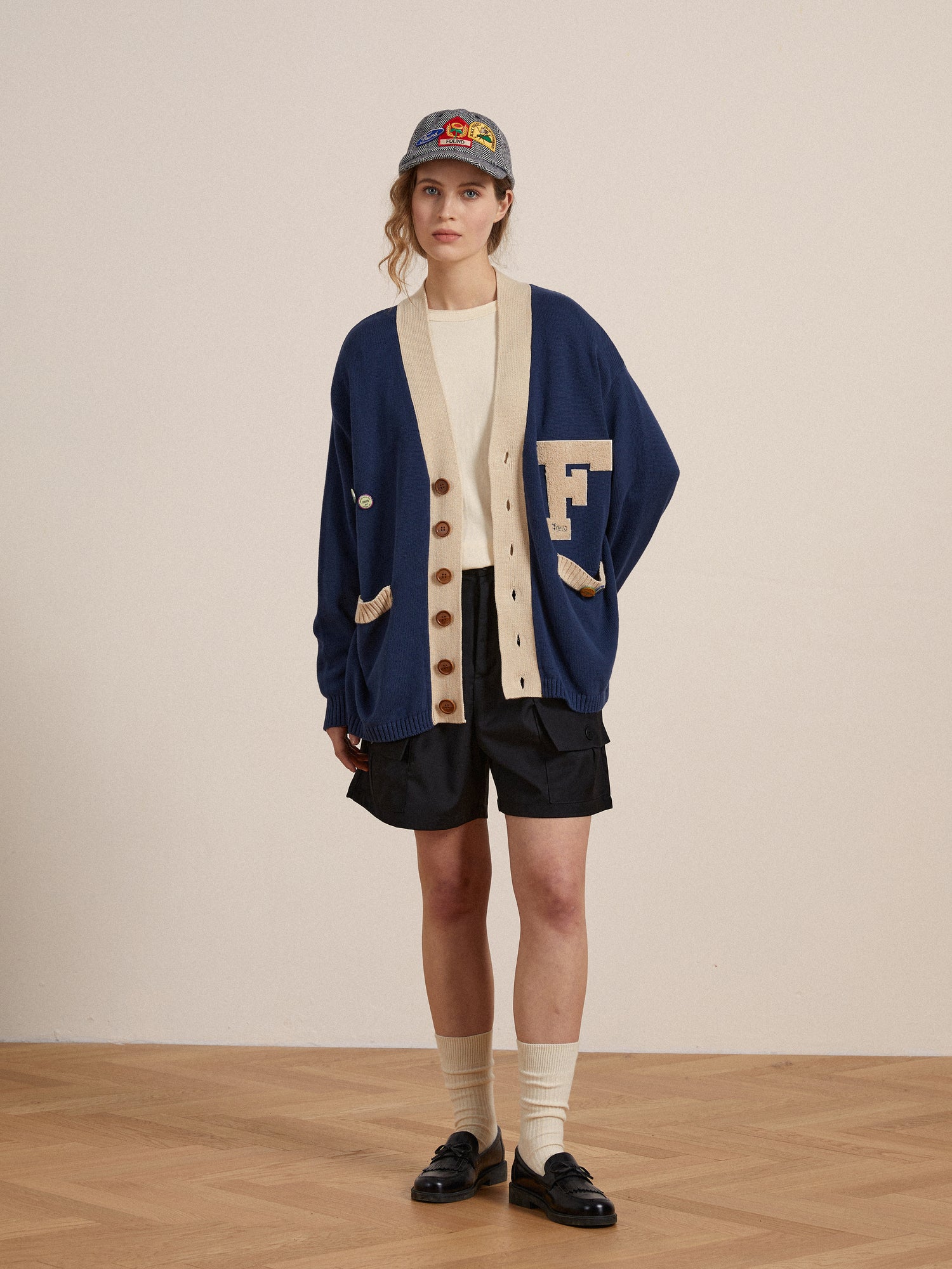 A woman wearing the customizable Found Laleh Varsity Contrast Cardigan and shorts.