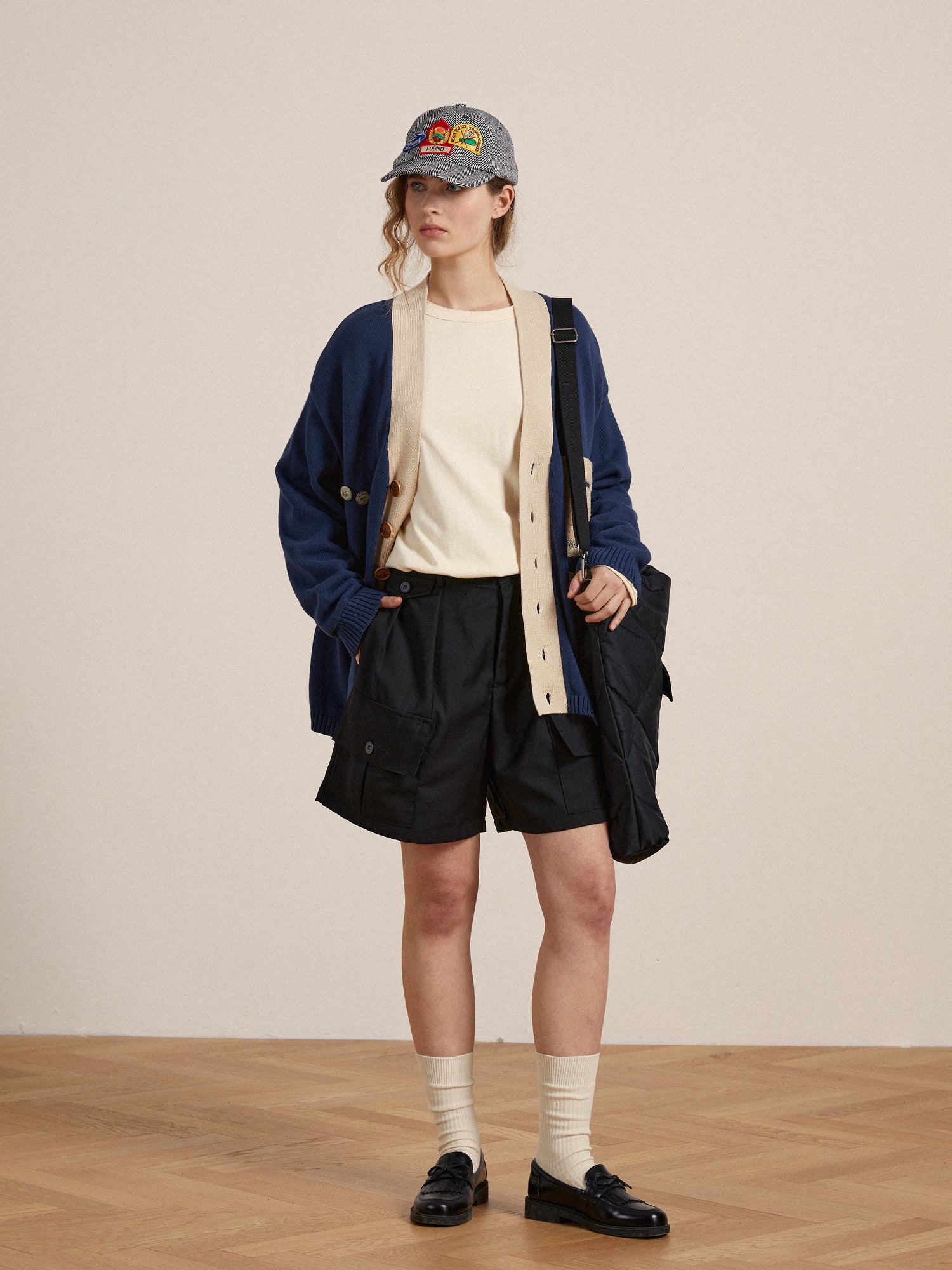 A woman in elegant Found Pleated Pocket Cargo Shorts and a hat is standing on a wooden floor.