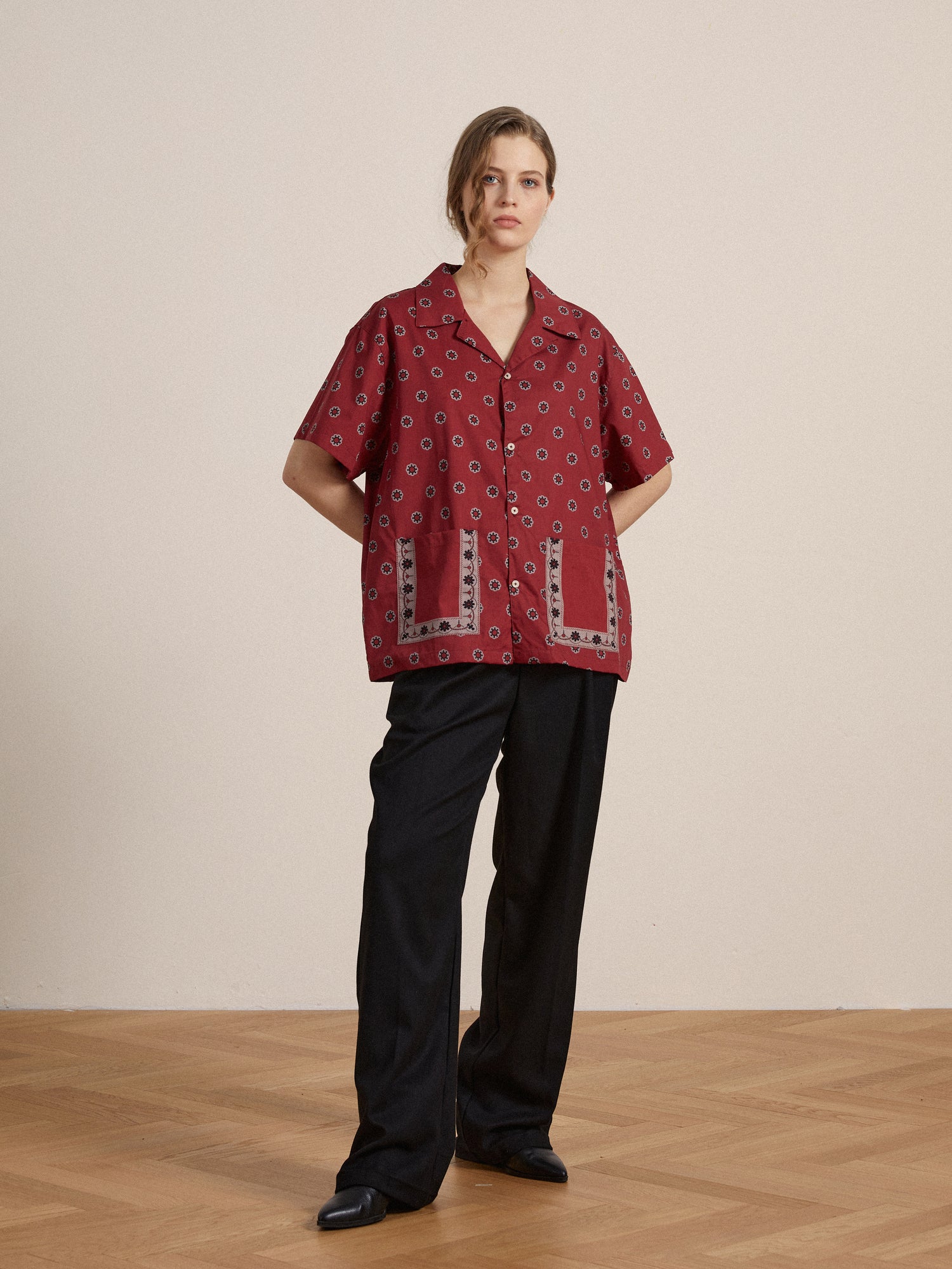 A woman wearing a Found Red Motif SS Camp Shirt and black pants.