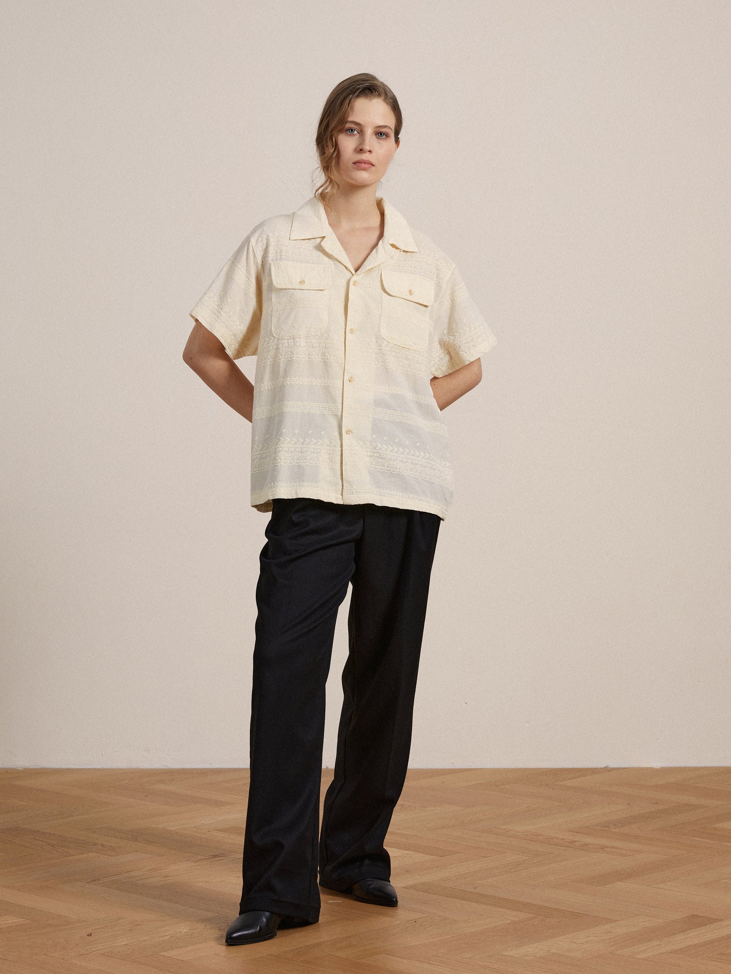 The model is wearing a Found Lace SS Camp Shirt with delicate lace detailing and black pants.