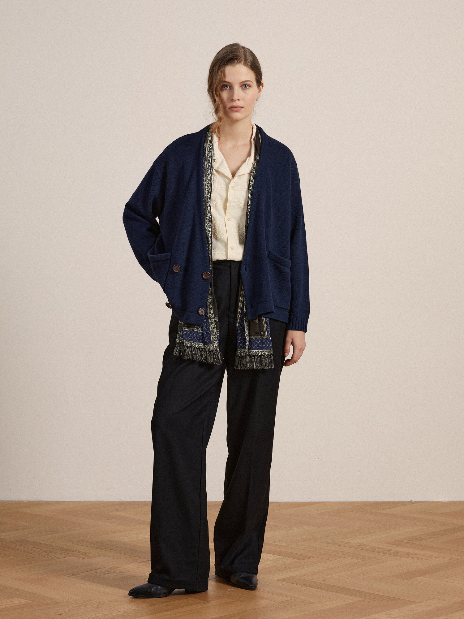 The model is wearing a navy, Larsi Double Breasted Knit Cardigan and black trousers.