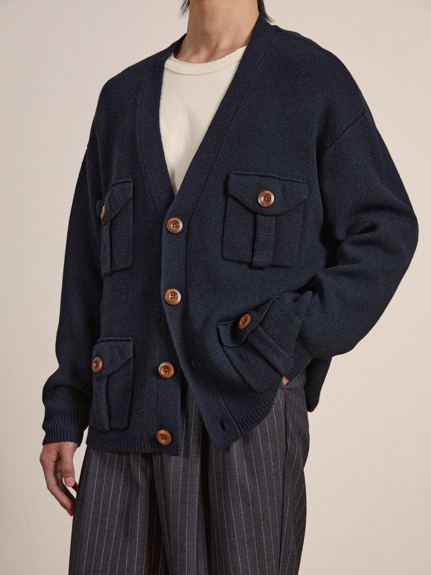 The model is wearing a navy Found Multi Pocket Cardigan with wooden buttons.