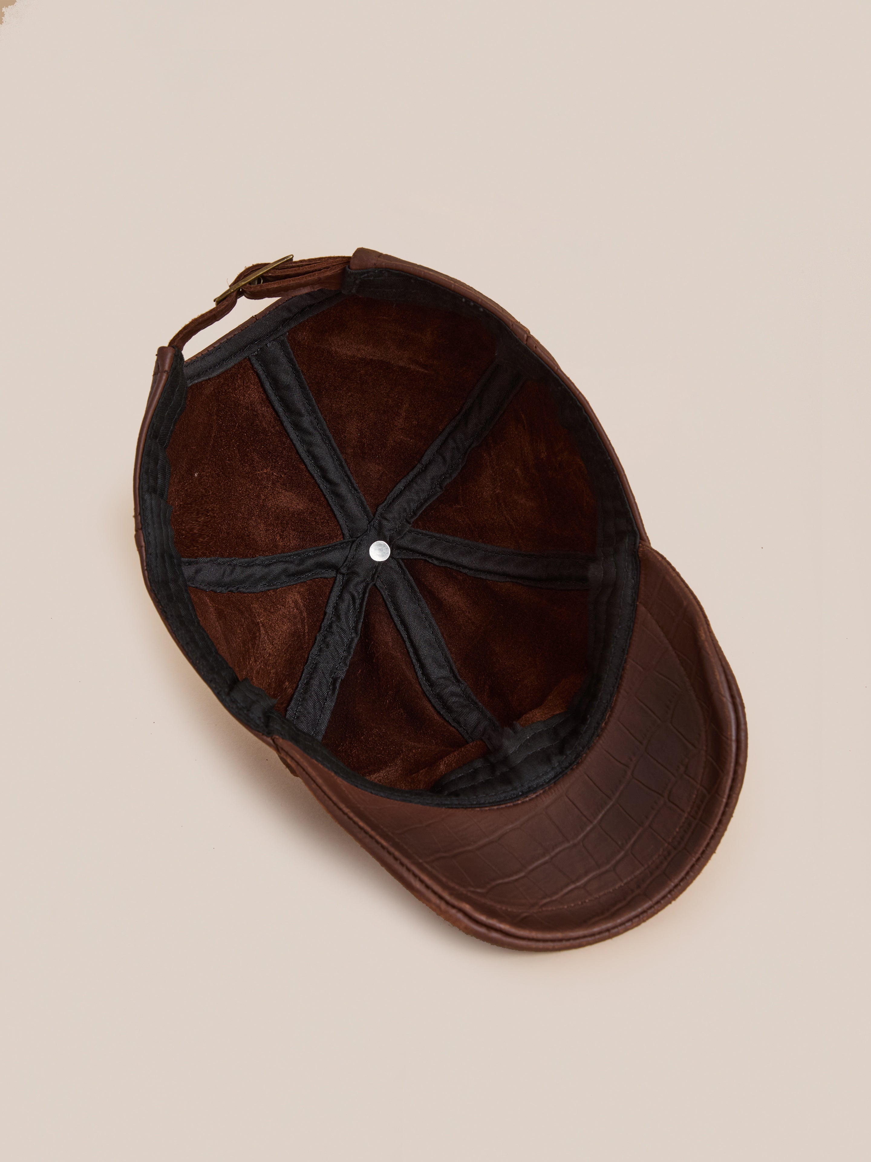 The Croc Embossed Distressed Leather Cap by Found is an adjustable brown hat with a crocodile pattern, featuring a soft lined interior and black internal bands, shown from above.