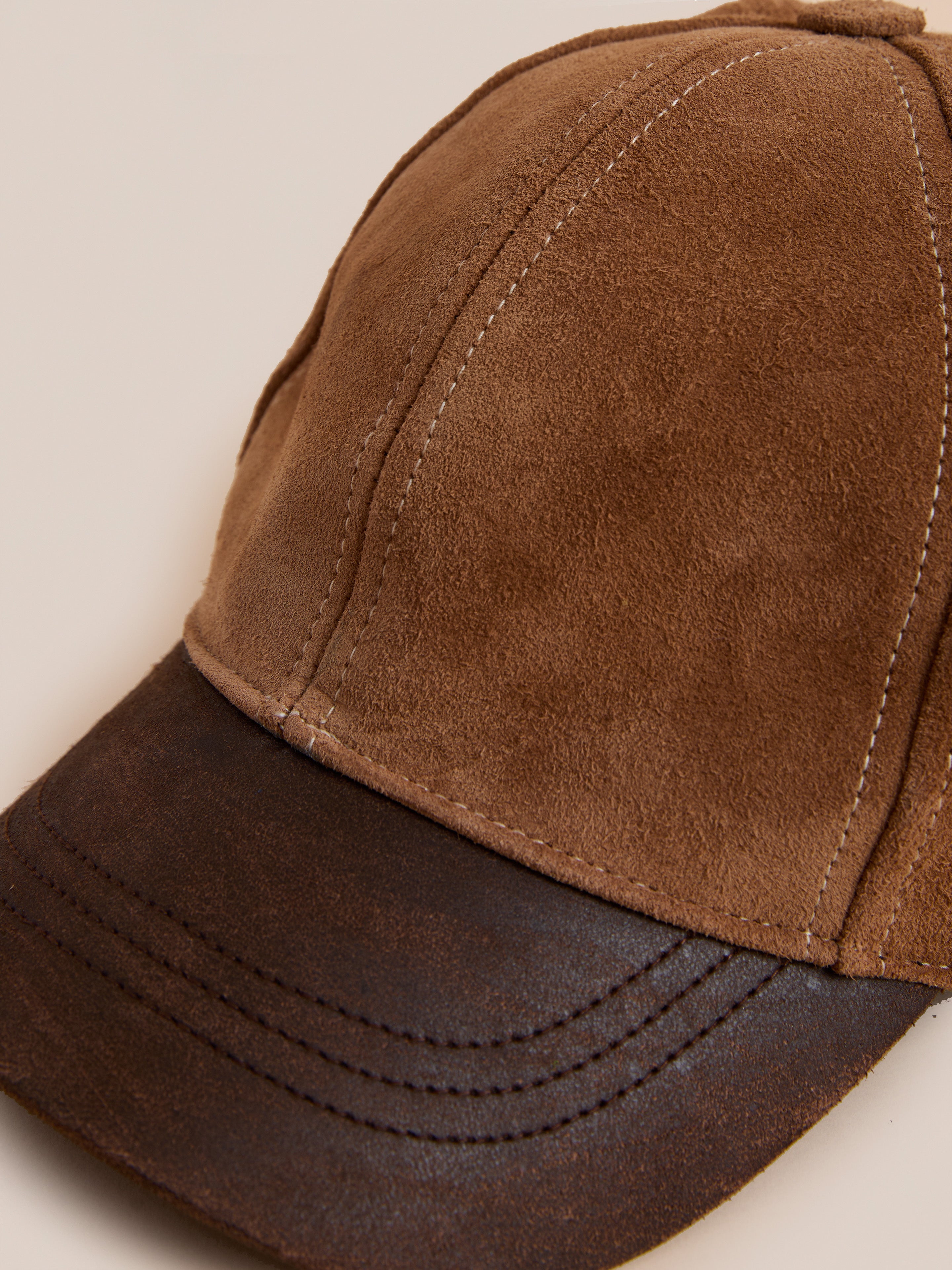 The Found Suede Leather Contrast Distressed Cap features a brown suede crown, a distressed brown leather brim, and visible stitching on both the crown and brim.