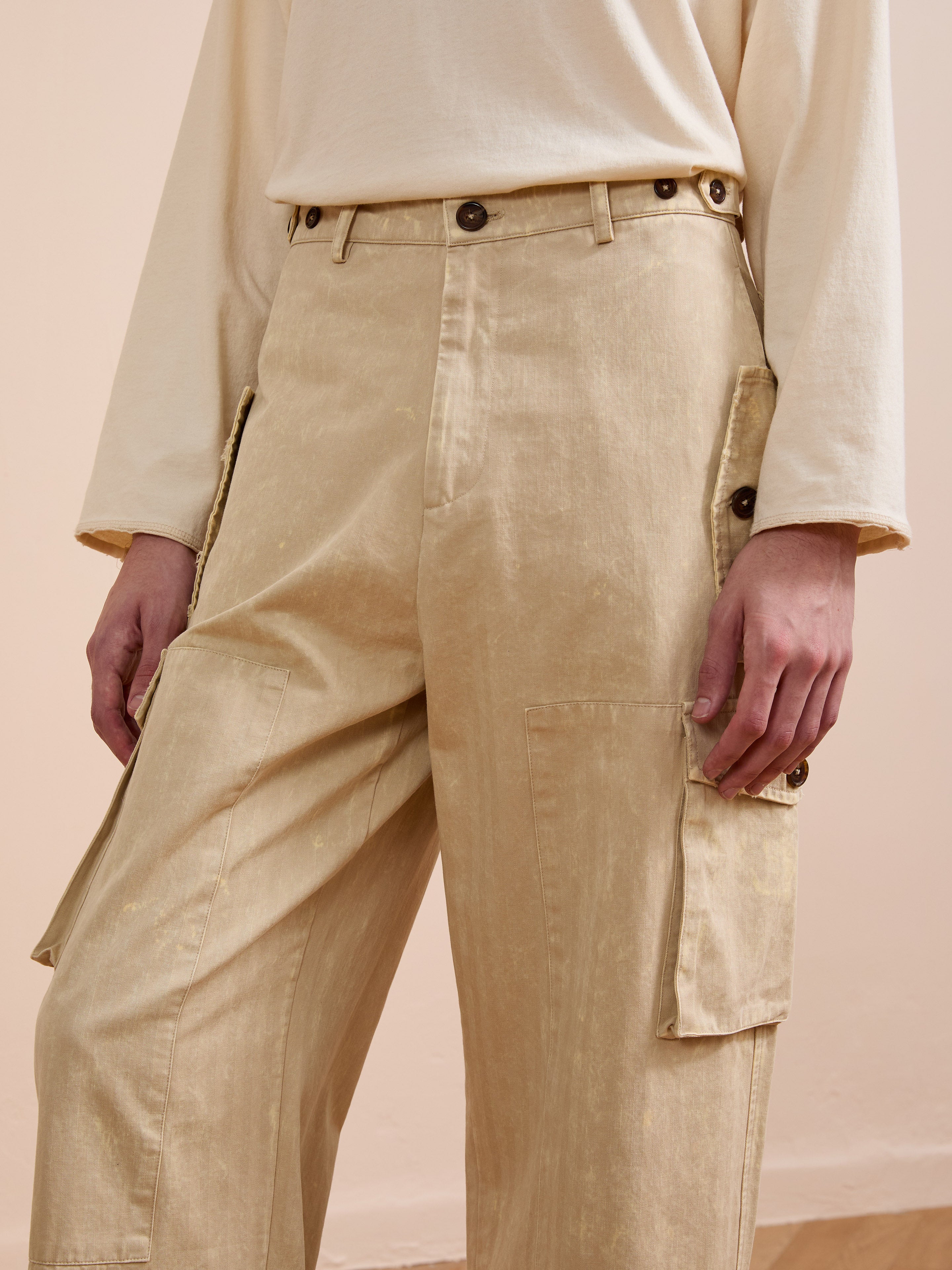 Wearing FOUND Utility Herringbone Paneled Pants and a beige long-sleeve top, this look offers an effortless, modern take on utility style, with hands relaxed by their sides in a minimal indoor setting.