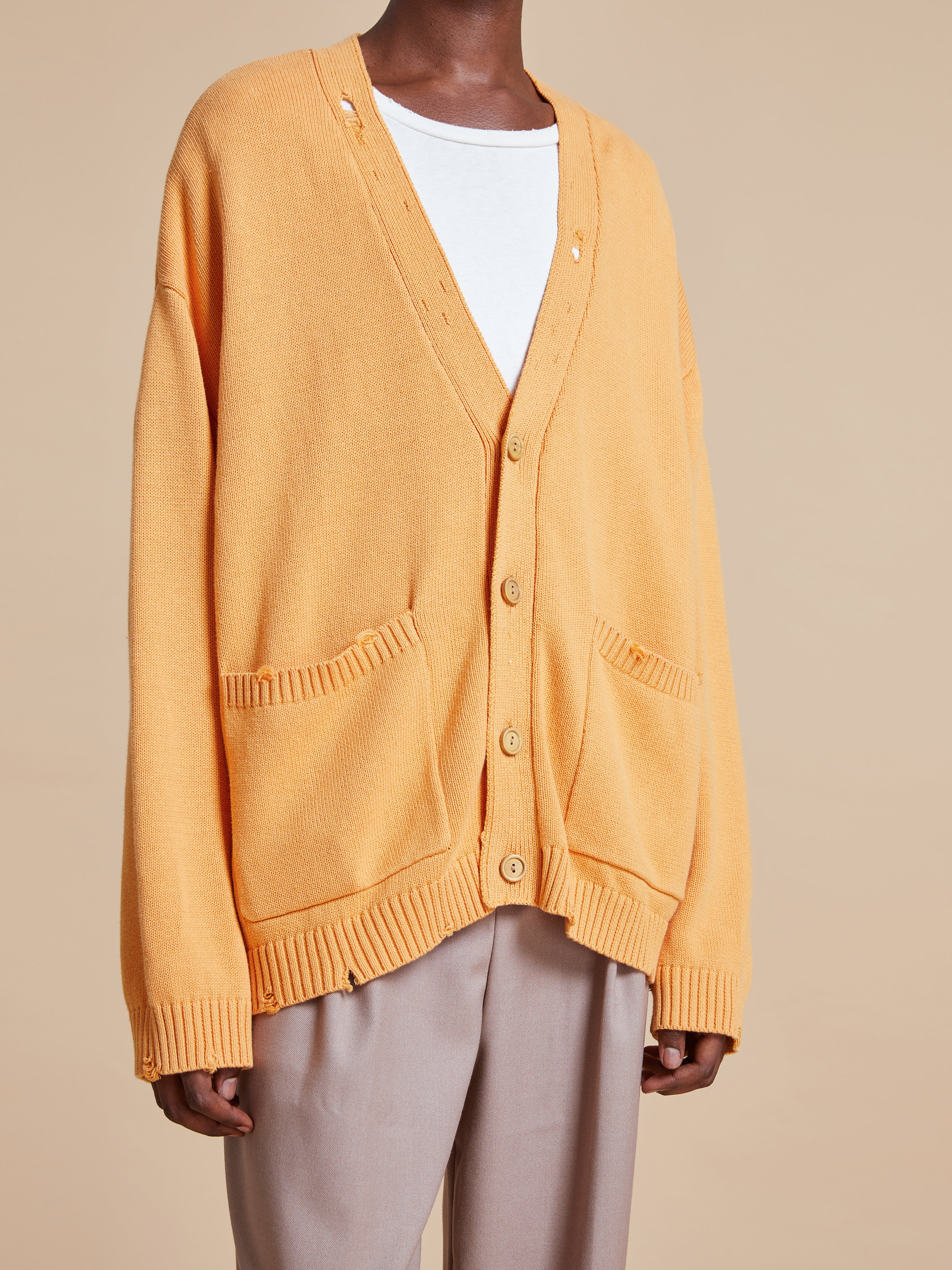 The model is wearing a Found Cadmium Distressed Cardigan sweater.