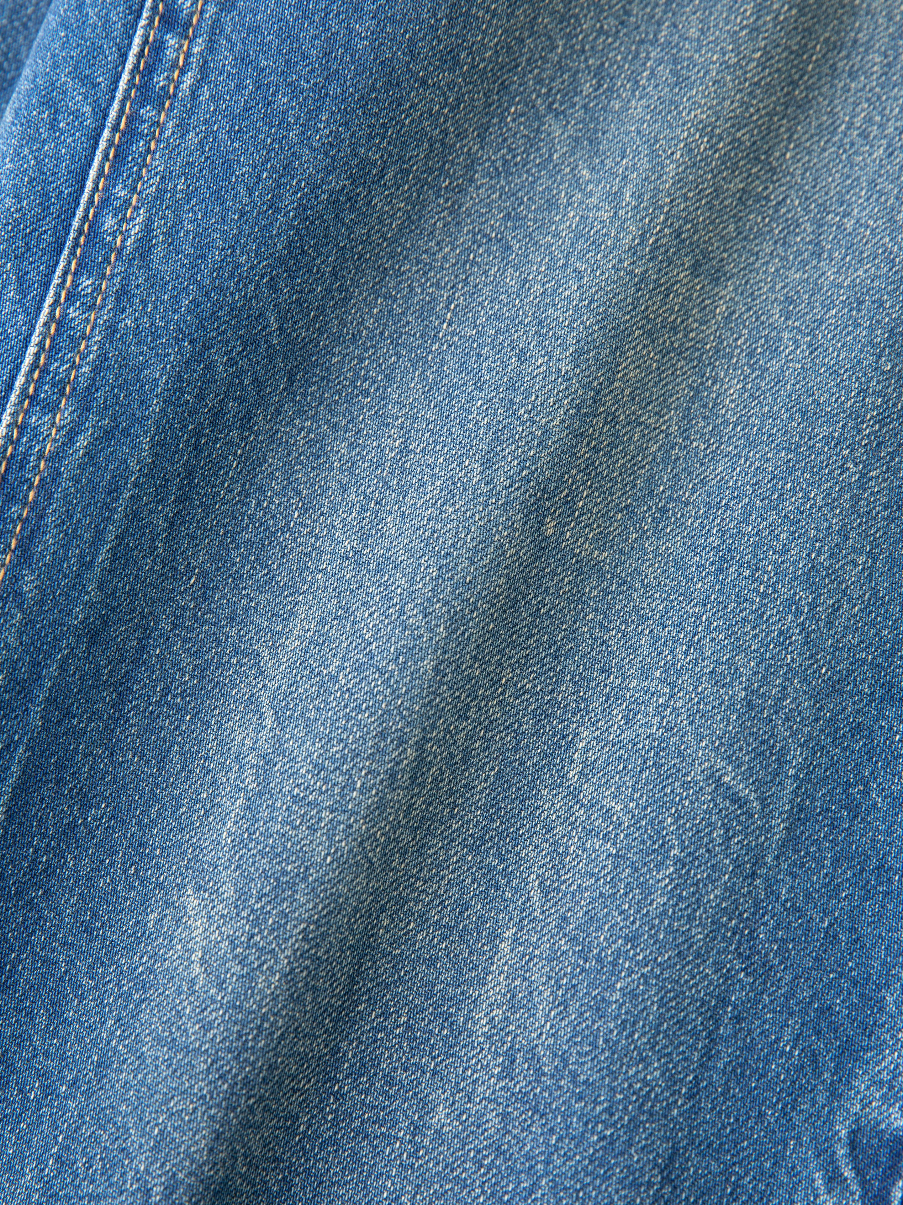 Close-up of blue denim fabric with visible stitching and texture variation, reminiscent of classic FOUND's Denim Carpenter Jeans, known for their utility pockets.
