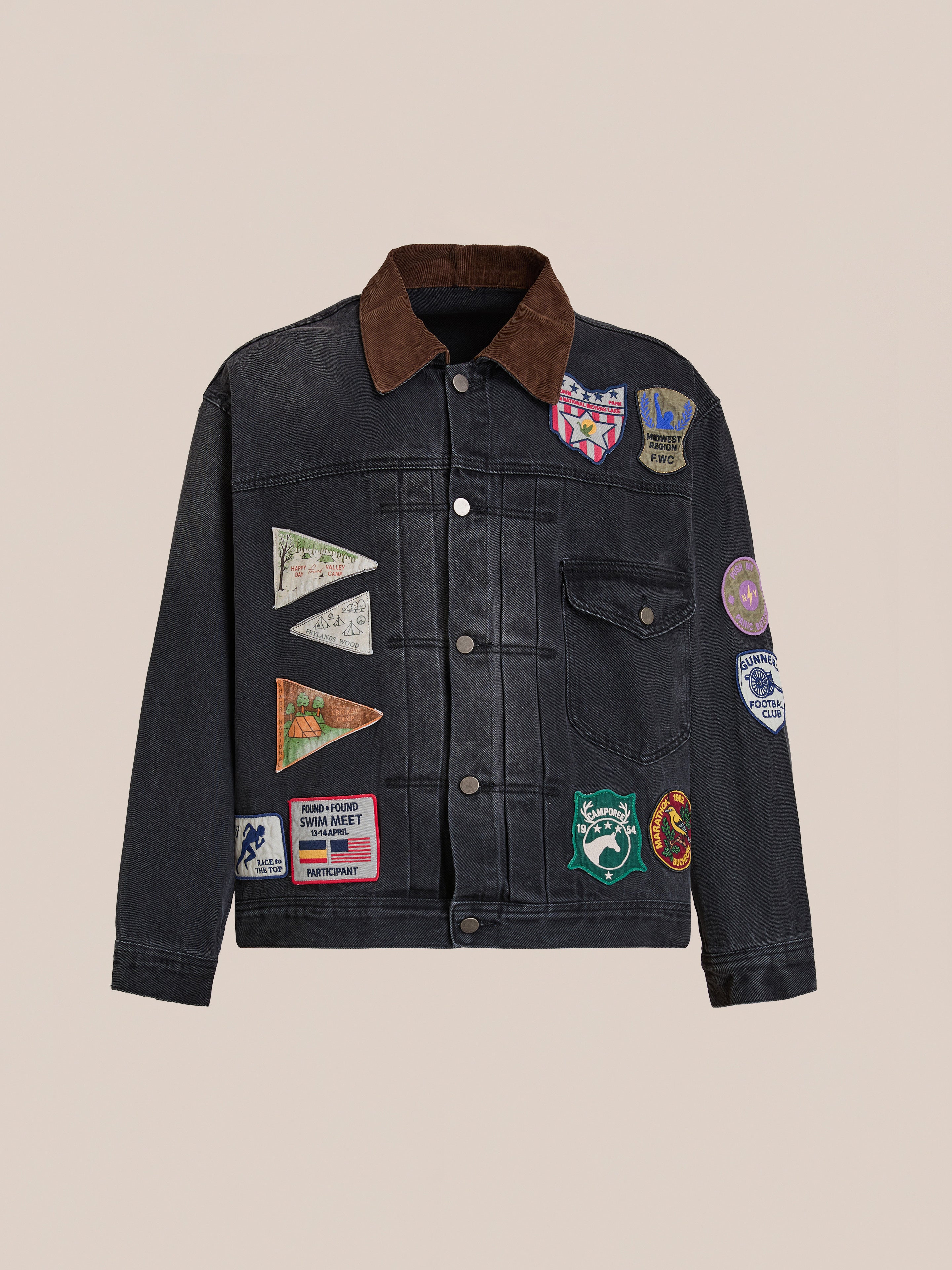 The FOUND Denim Patchwork Jacket features a vintage look with a corduroy collar and is adorned with colorful Americana patches and badges on the front and sleeves.