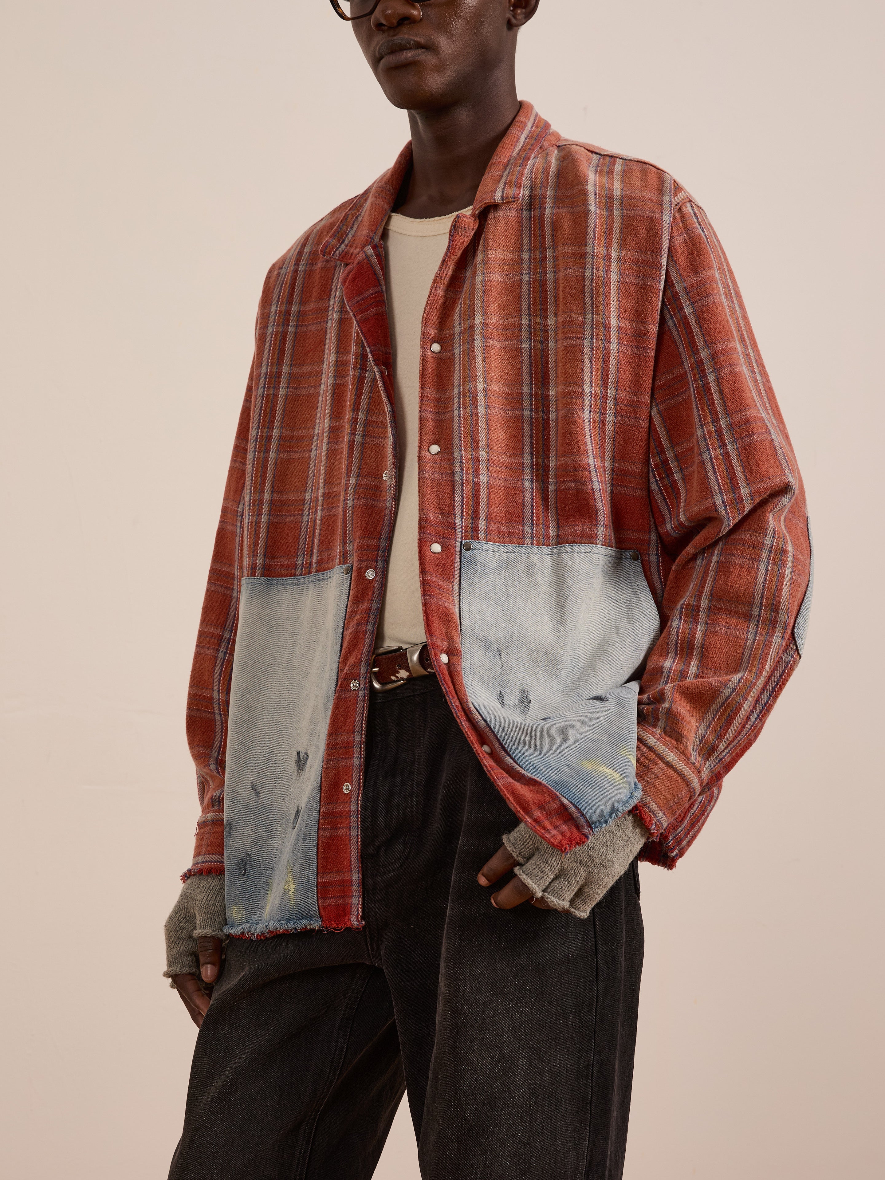 A person wears the FOUND Plaid Denim Shirtâa unisex relaxed fit with large faded denim carpenter pocketsâlayered over a white tee, paired with dark jeans and fingerless gray gloves.