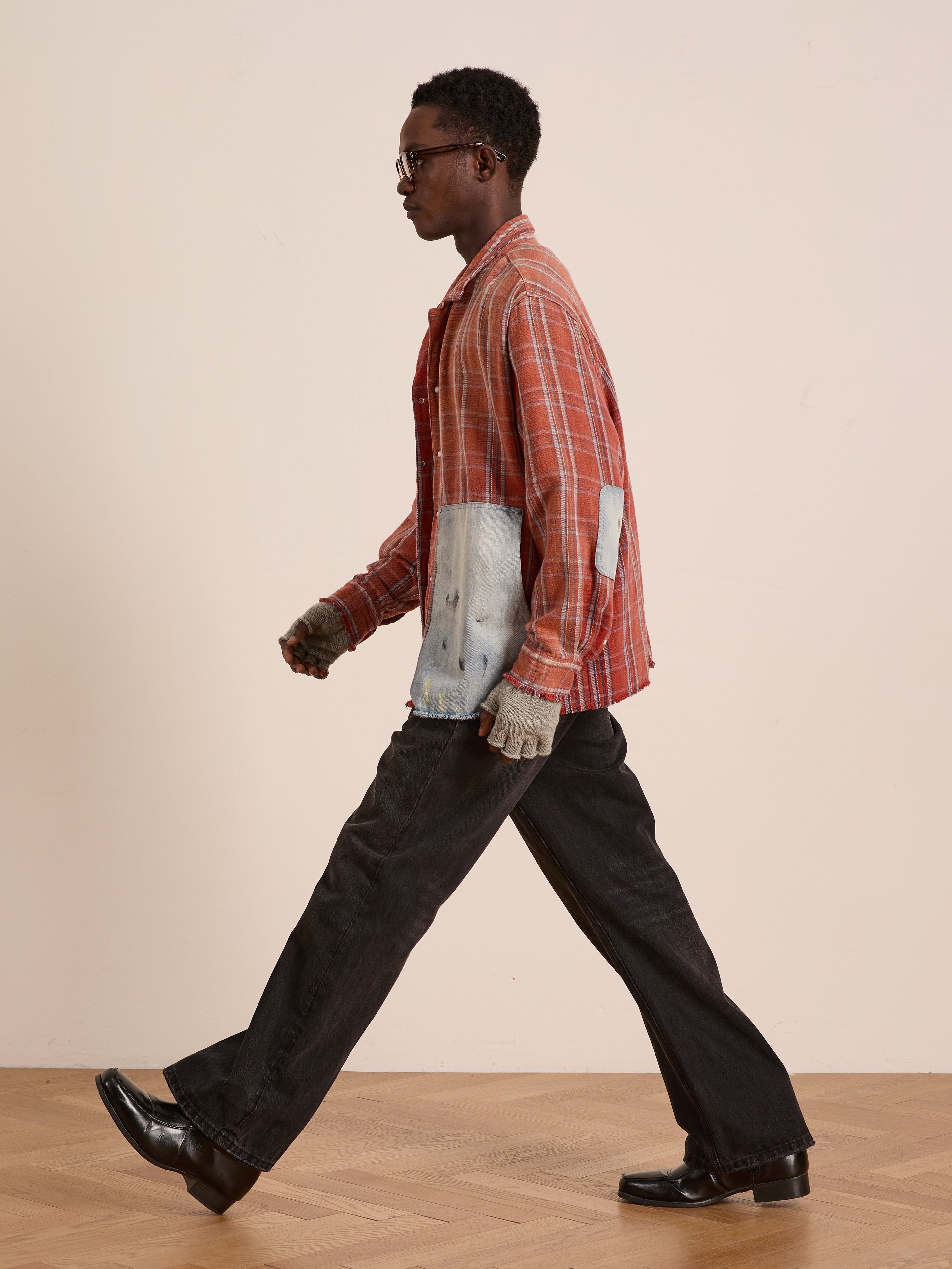 Someone wears the FOUND Plaid Denim Shirt—a unisex, relaxed-fit orange plaid with denim carpenter pockets—paired with black pants, gloves, and black shoes while walking indoors on a wooden floor against a plain background.