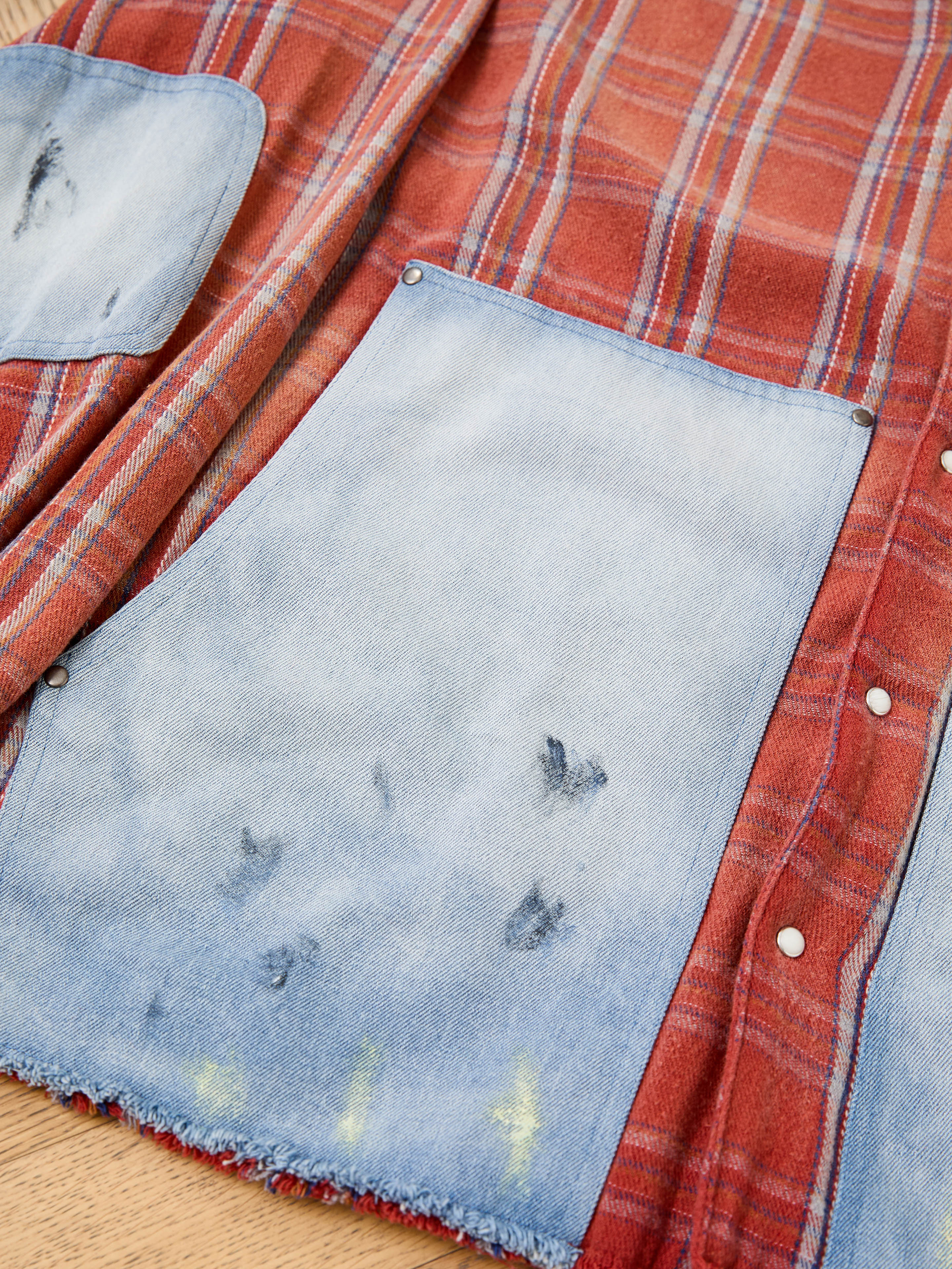 The FOUND Plaid Denim Shirt features bold red and orange plaid with denim carpenter pockets and visible wear, offering a rugged, unisex workwear look.