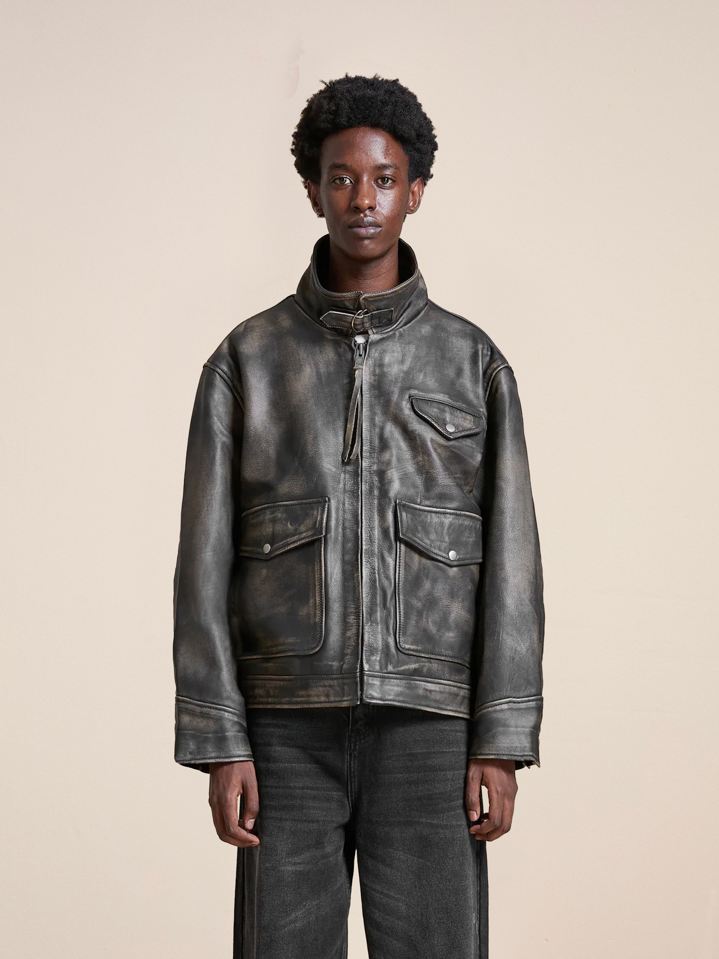 A person wearing the Found Distressed Leather Pocket Jacket and jeans stands against a plain background, exuding an effortlessly cool vibe.