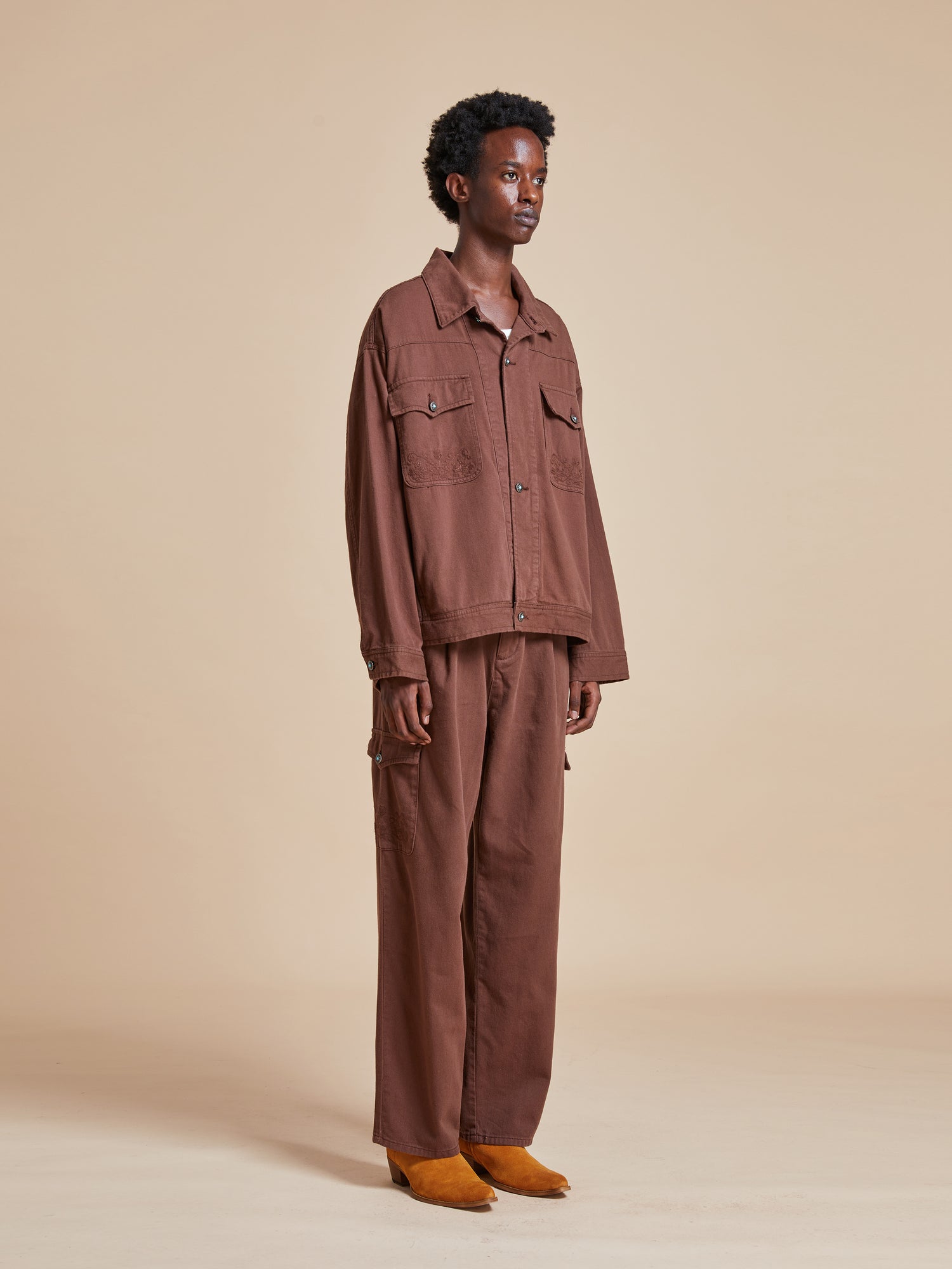 The model is wearing a brown Dusky Western Trucker Jacket and a brown cargo pants.